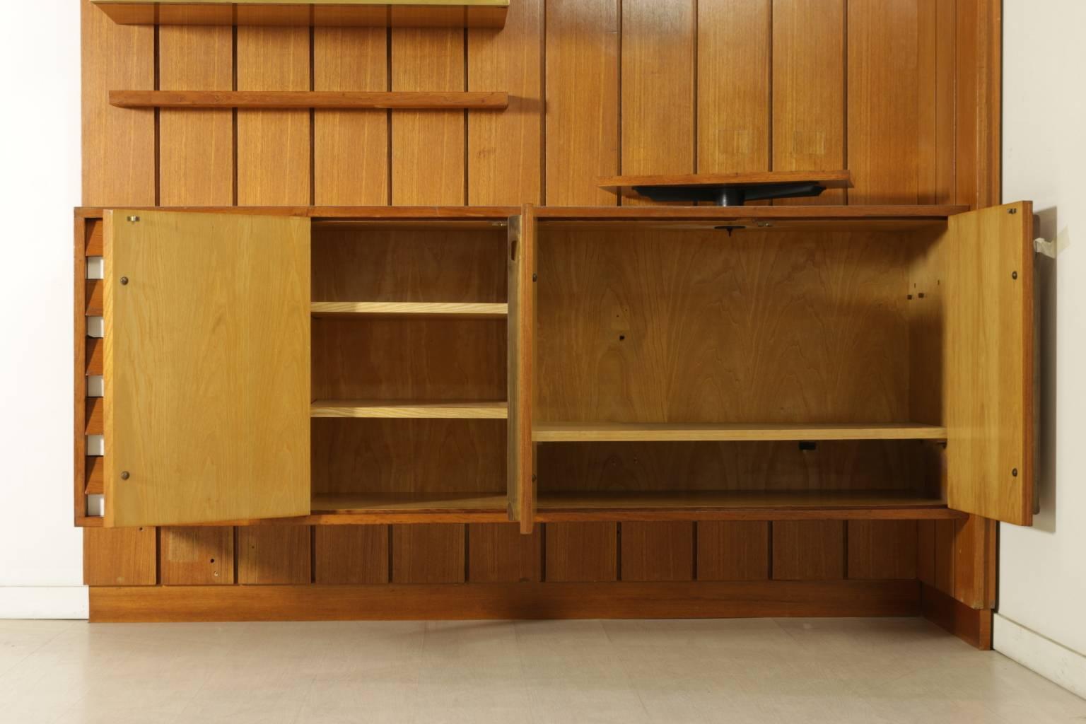 A sitting room cabinet designed for a private client in Milan, composed of wainscoat, closed and open compartments, shelves, adjustable TV stand. Teak veneer, formica, brass, screen printed decorative panel. Manufactured in Italy, 1960s.
