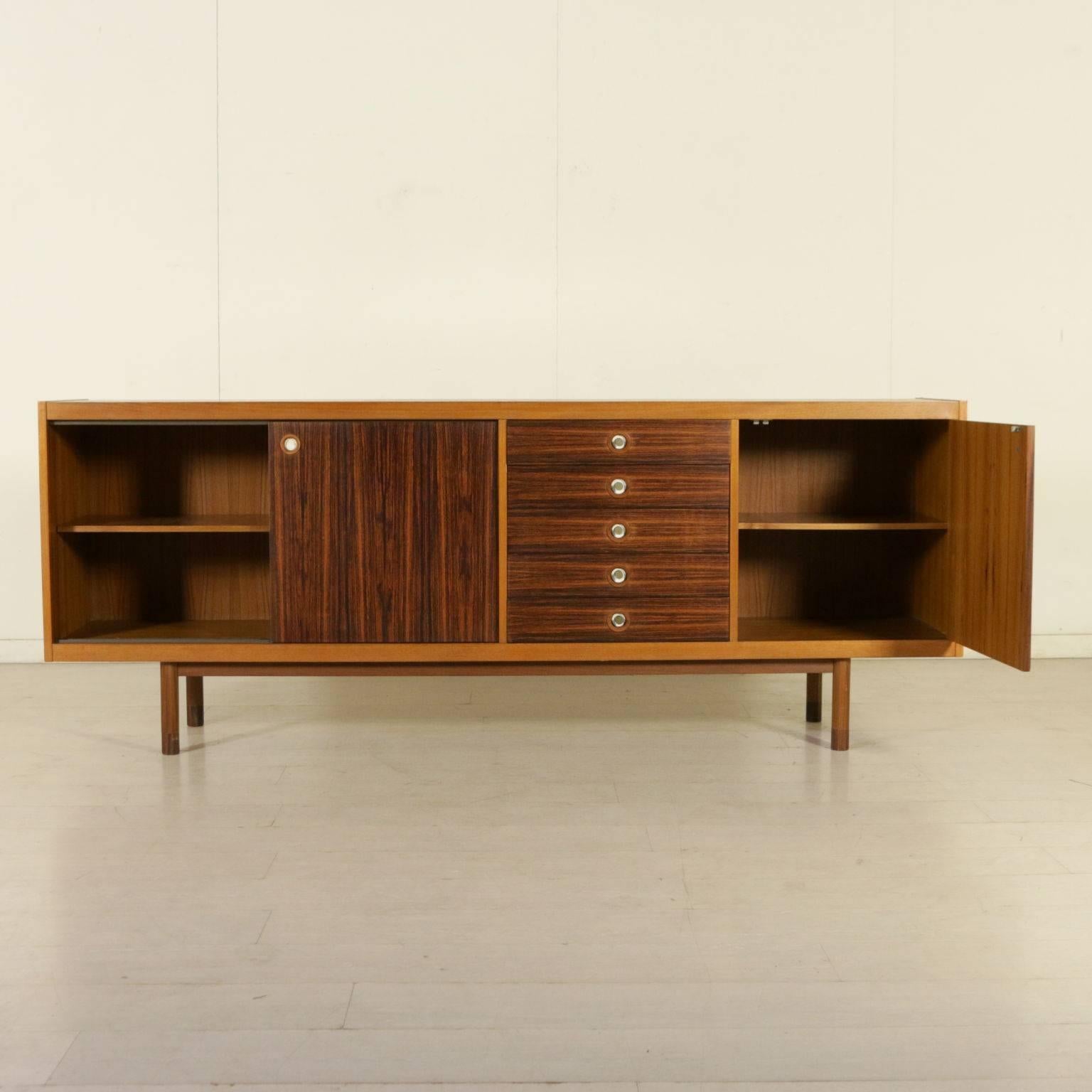 A sideboard with hinged doors, sliding doors and five drawers. Teak and rosewood veneer, brass handles. Manufactured in Italy, 1960s.