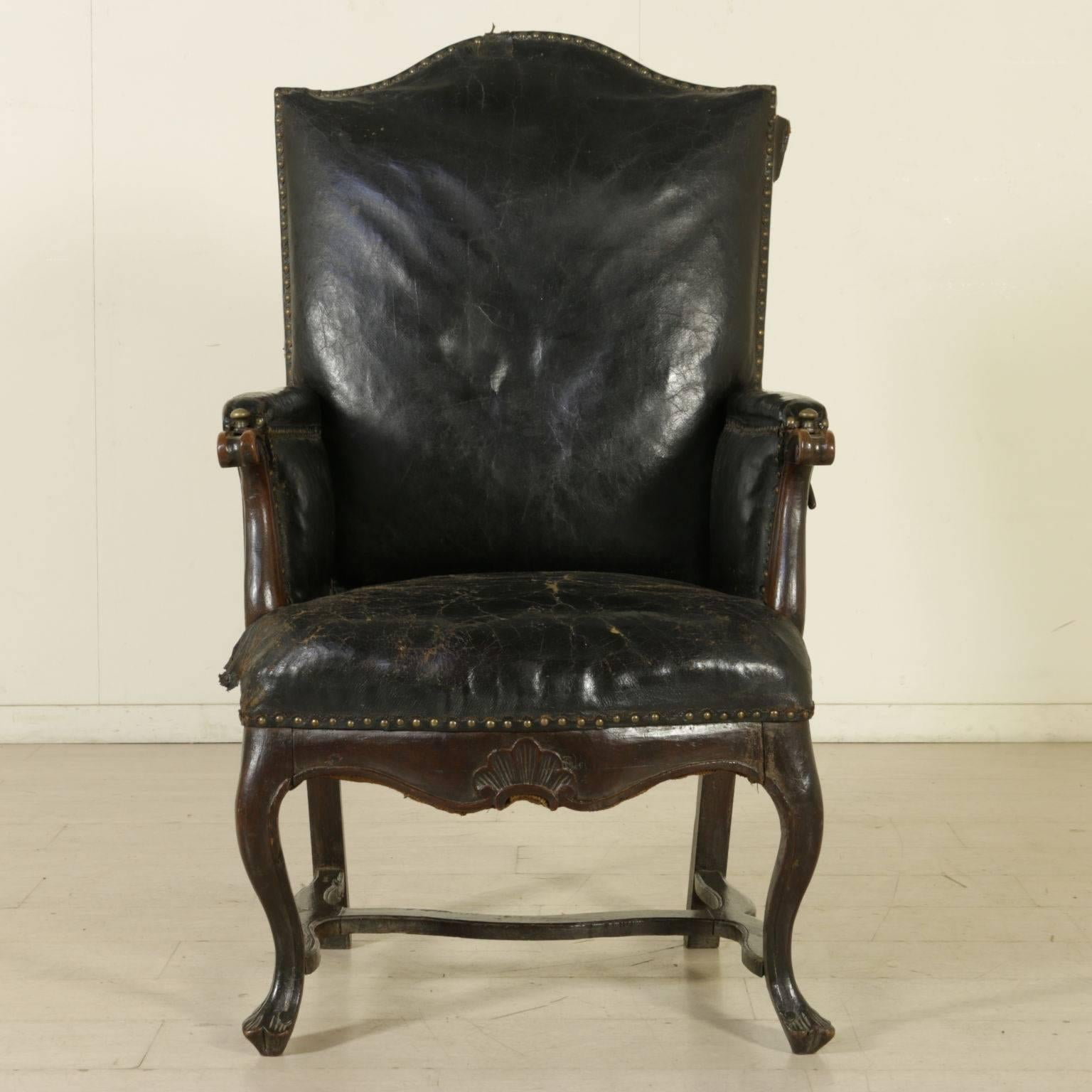 An important walnut armchair with moved and carved legs, joined by shaped crossbar. The armrests, decorated with curls, hide iron supports with bronze knobs functioning as a tray holder. The shaped backrest is reclining and adjustable through side