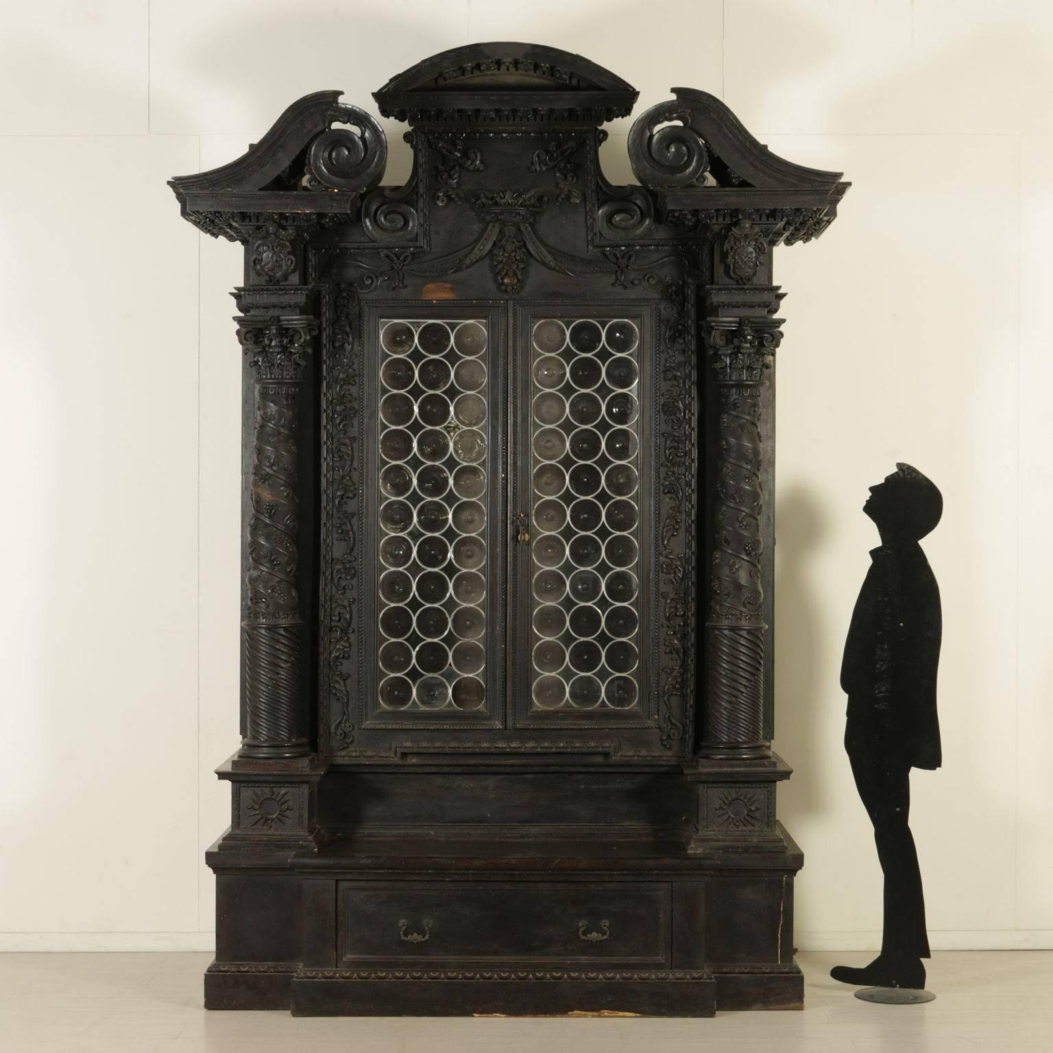 An important Renaissance Revival two-door walnut veneered bookcase with artistic glasses. It features a pair of towers with Corinthian capitals ending in a tripartite tympanum. Richly carved with floral and vegetal patterns and a crown with drapery.