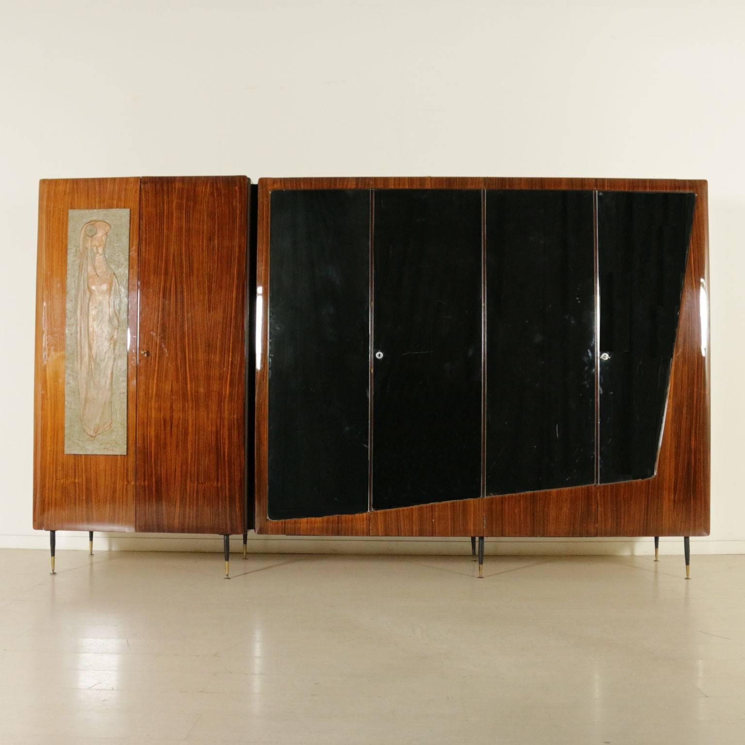 A wardrobe, rosewood veneer with mirrors, decorative wood panel, metal legs with brass ferrules. Manufactured in Italy, 1950s-1960s.