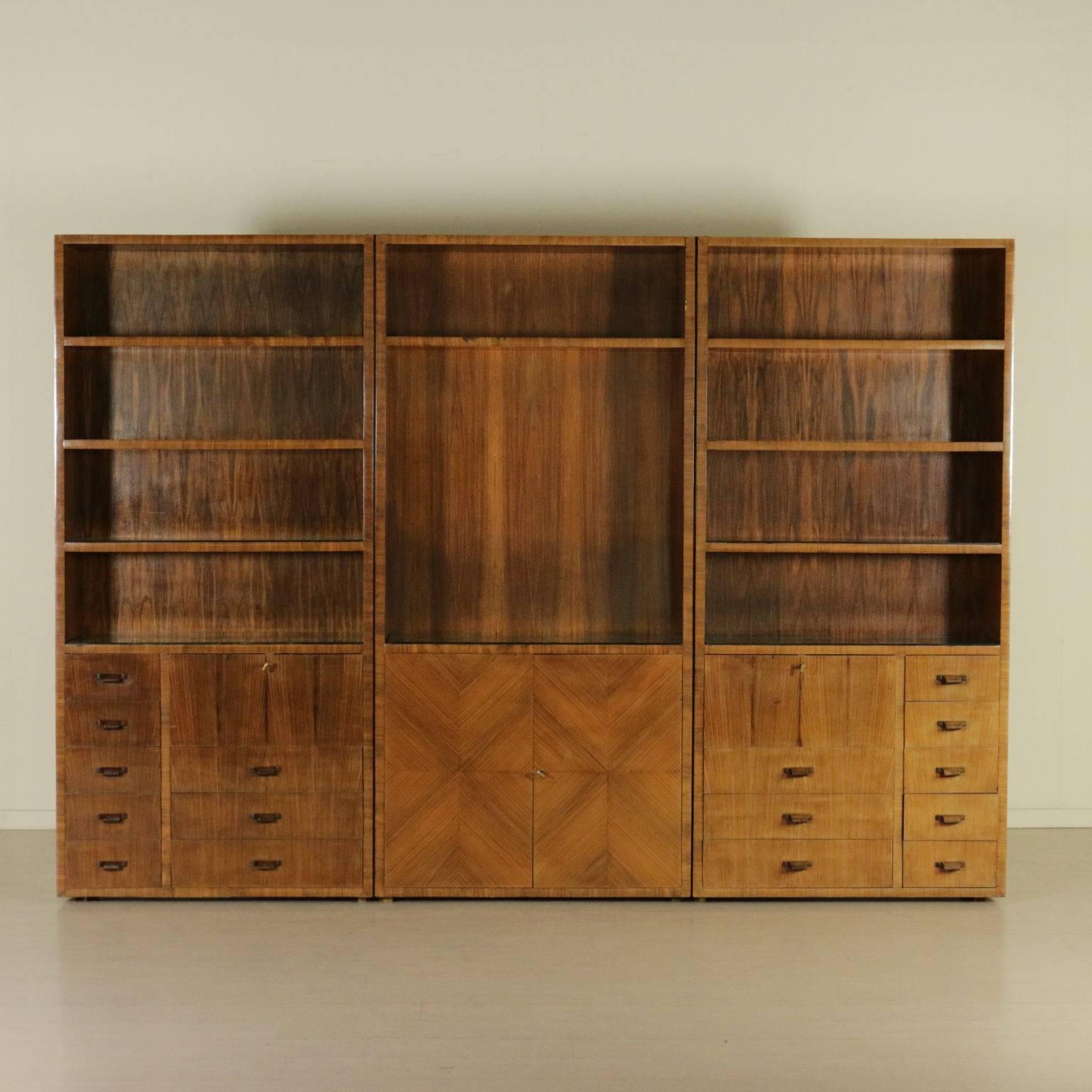 A bookcase, three elements with doors and drawers. Rosewood veneer, transparent glass leaning on some shelves. Manufactured in Italy, 1940s.
