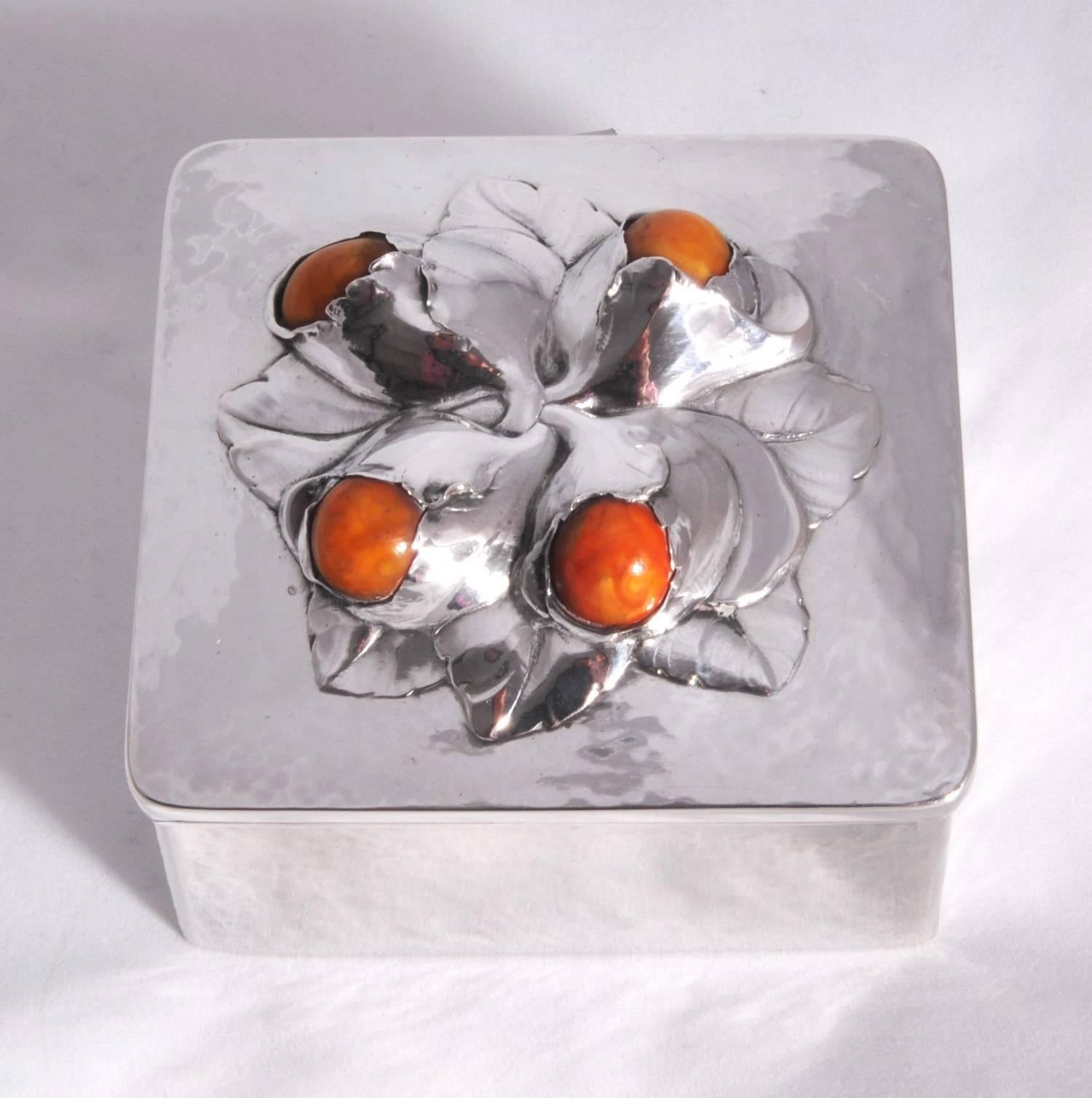 A beautiful Evald Nielsen silver box set with Baltic amber within a budding flower design. The piece is hallmarked for Denmark, Copenhagen, 1914 with the EN makers mark and Evald Nielsen signature. The design is typical of Nielsen's work which is