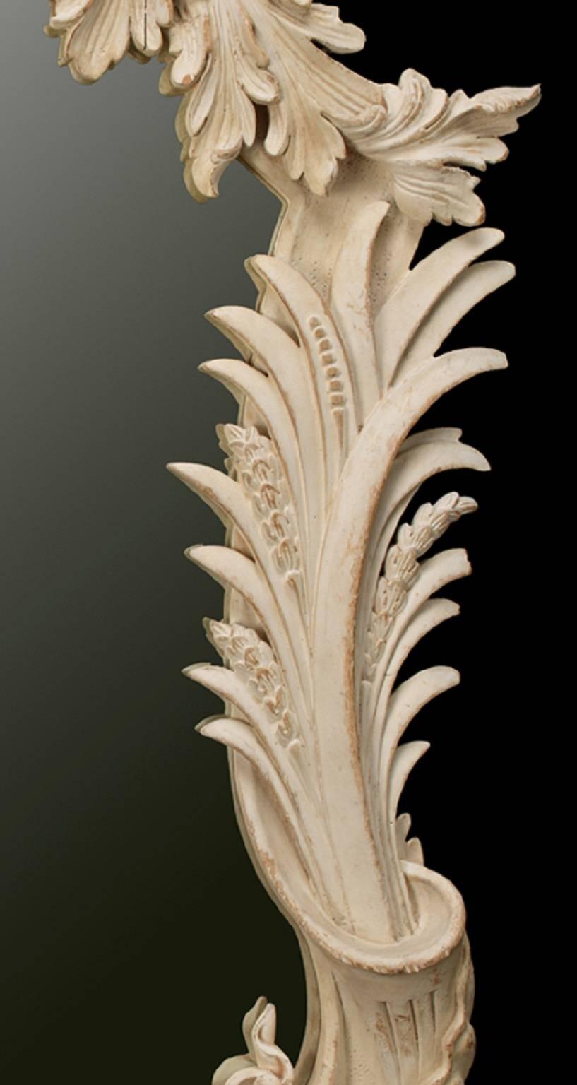 A pair of Vardy mirrors. The frame is carved with scallop shell decoration, centred by a female mask crest above acanthus leaves and cornucopia to the sides. Finished in an aged gesso and distressed paint finish.