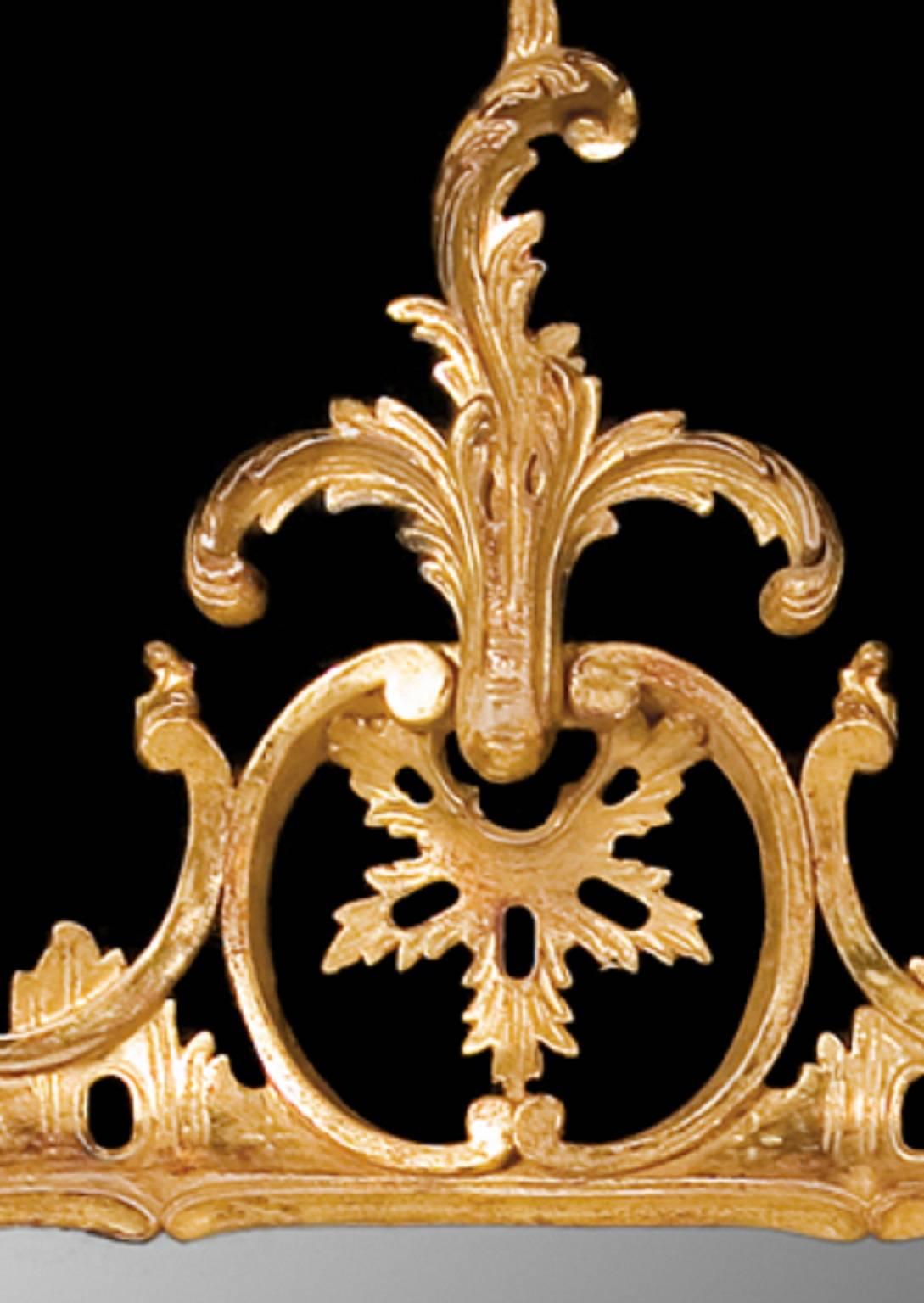 This rectangular giltwood looking glass mirror is carved in a light and open Rococo style frame. The mirror plate is set within vigorously drawn C-scrolls, acanthus leaves, flowers and leaves and with an acanthus leaf spray cresting.

This is the