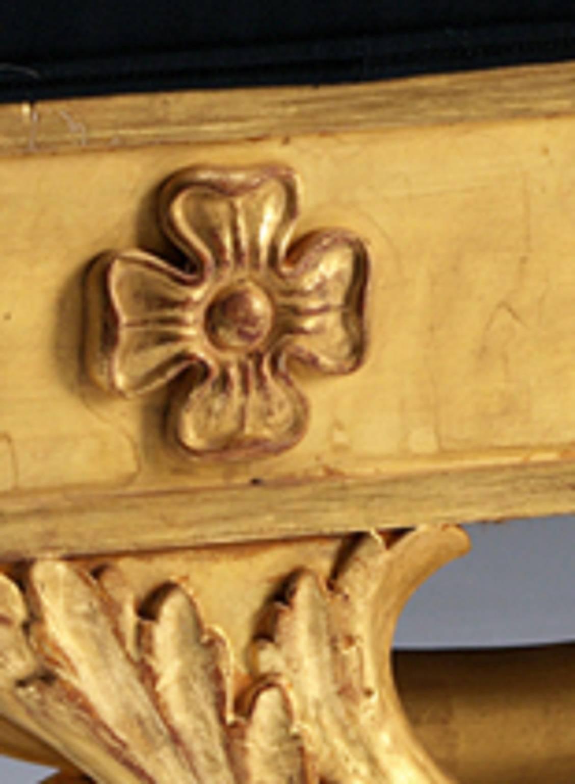Ein vergoldeter Regency-Fenstersitz aus Holz, dessen getäfelter Fries mit geschnitzten Paterae verziert ist und von einem naturalistisch geschnitzten 
