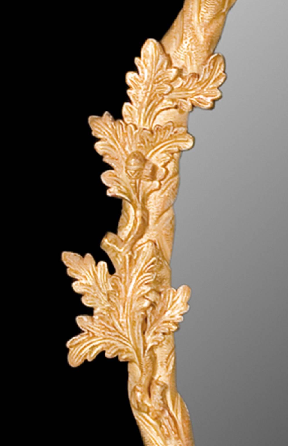 The carved giltwood crossed boughs of branches that form the frame of this looking glass are decorated with oak leaves and acorns which are held at the base by a pierced cartouche. The ribbon tied top supports the leaf carved cresting of leaves.

We