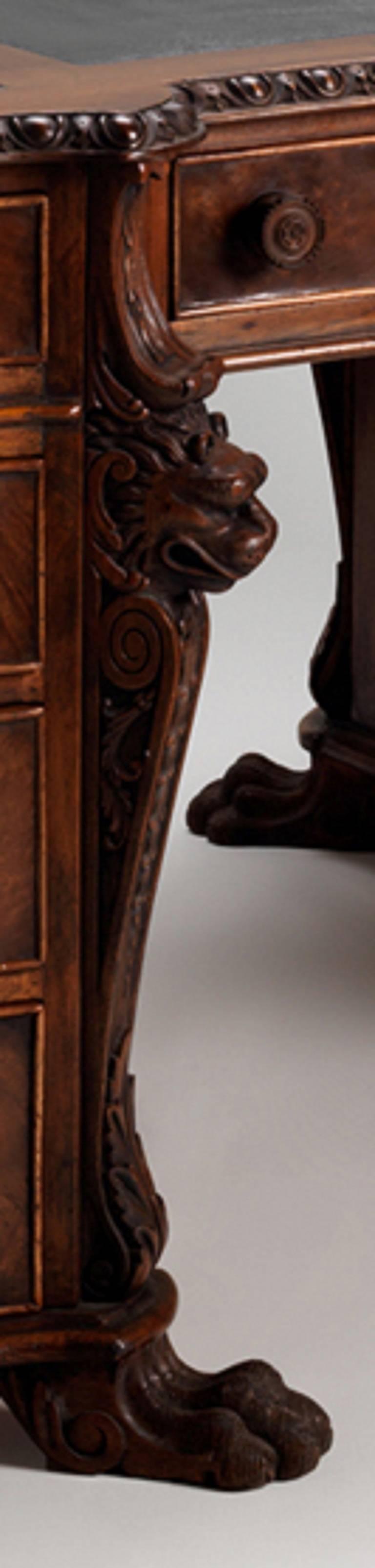 The desk has an egg-and-dart moulded and serpentine shaped top with leather writing surface. The opposing sides are fitted with a frieze drawer flanked by four graduated drawers to each pedestal, lion mask and acanthus canted angles, on paw