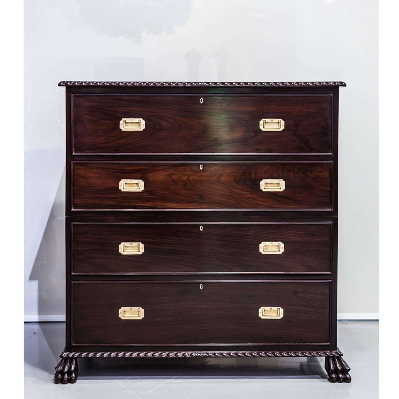 A British colonial campaign secretaire chest of drawers in two sections. The top portion with two long drawers. 
The top drawer opens to reveal a secretaire interior fitted with several (secret) compartments and drawers. The writing surface with