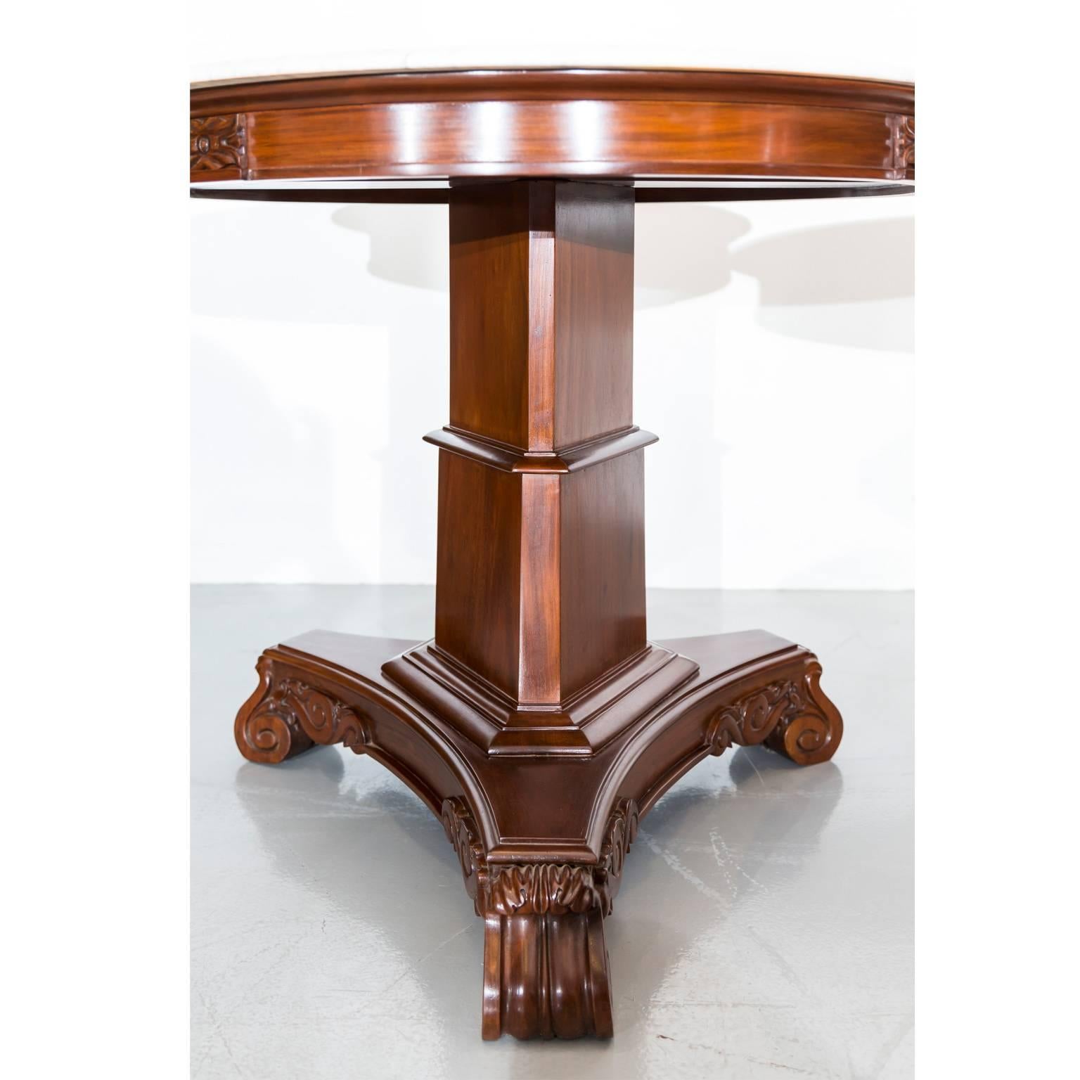 A pair of British Colonial mahogany side tables with a new beveled edge marble top. 
The top with a nicely carved apron rests on a tapered pillar surrounded with a wide molded band at the bottom. The central support rests on a carved triangle-form