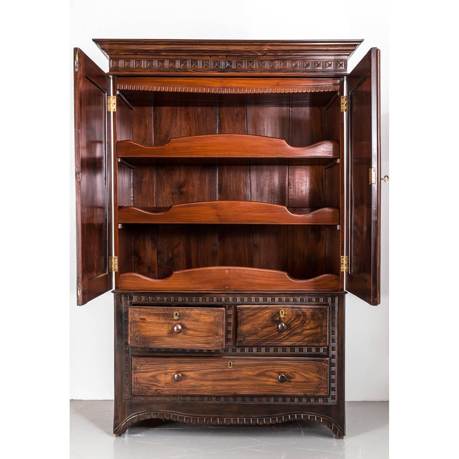 A Portuguese colonial rosewood cupboard beautifully designed and crafted with a pattern exclusive to Portuguese India. 
The double doors have floating panels that display a sunburst carving and floral carving in the corners. The interior in