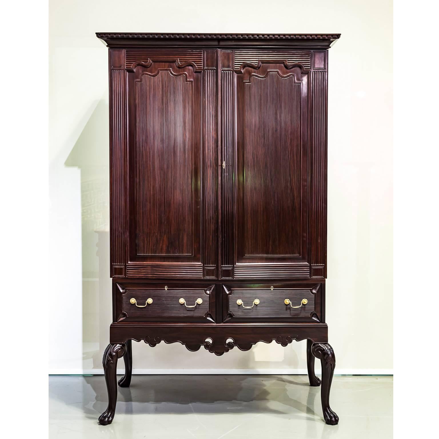 An elegant Portuguese colonial rosewood cupboard on stand with an overhanging rectangular top. The double doors are crafted with an arched cushion moulded panel and with a pattern exclusive to Portuguese India. The doors open to an interior with two