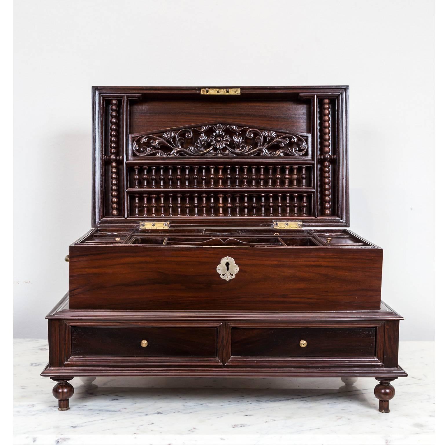 A beautifully grained rosewood, Dutch colonial box with a silver escutcheon and brass lift handles on the side.
The box opens to reveal a fitted interior with several small compartments and a detachable tray which conceals more storage space. A