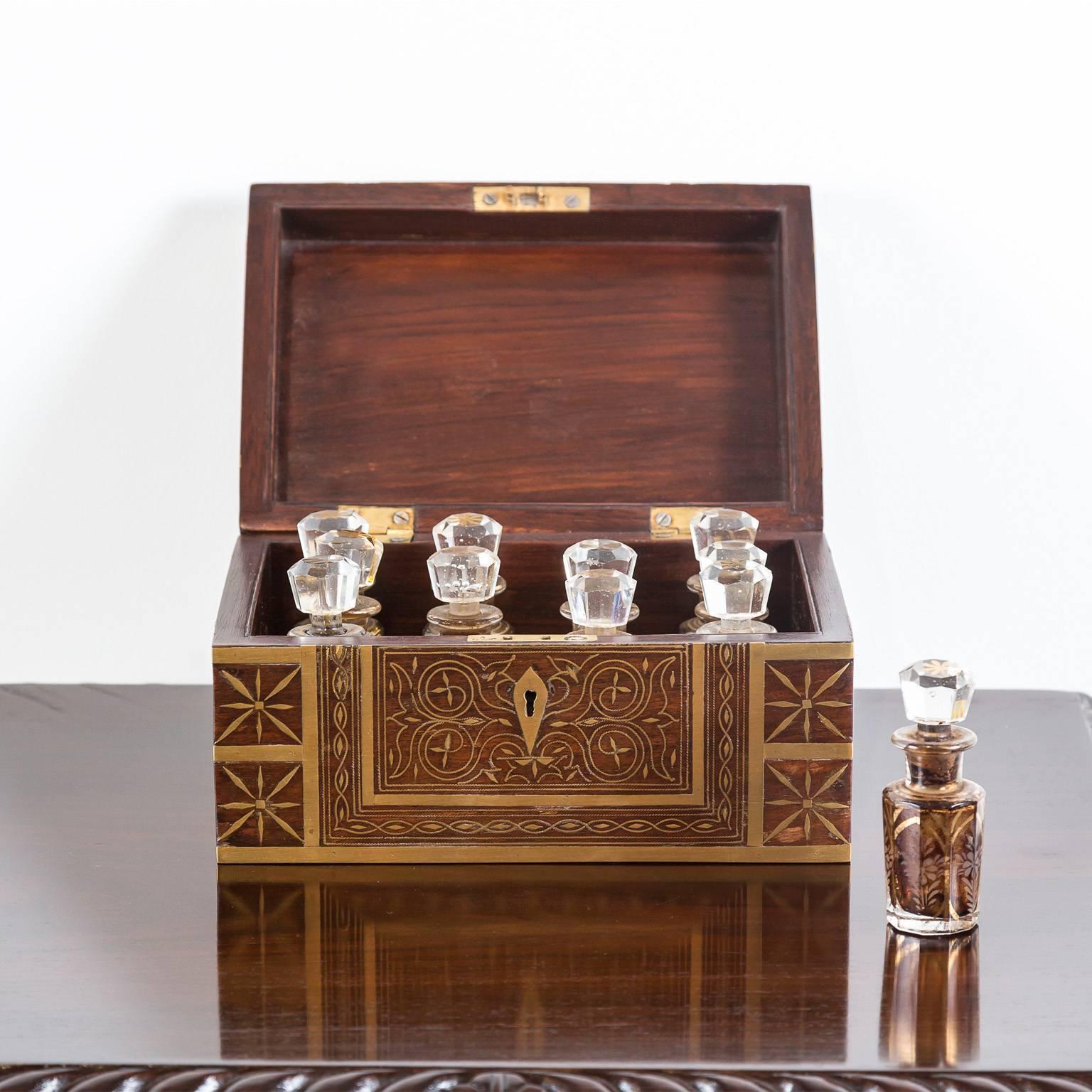 A beautiful British Colonial rosewood perfume box, profusely inlaid with delicately shaped pieces of brass design. Brass strapping to the edges, brass escutcheon plate and brass recessed lift handles on the sides.
The box opens to reveal a