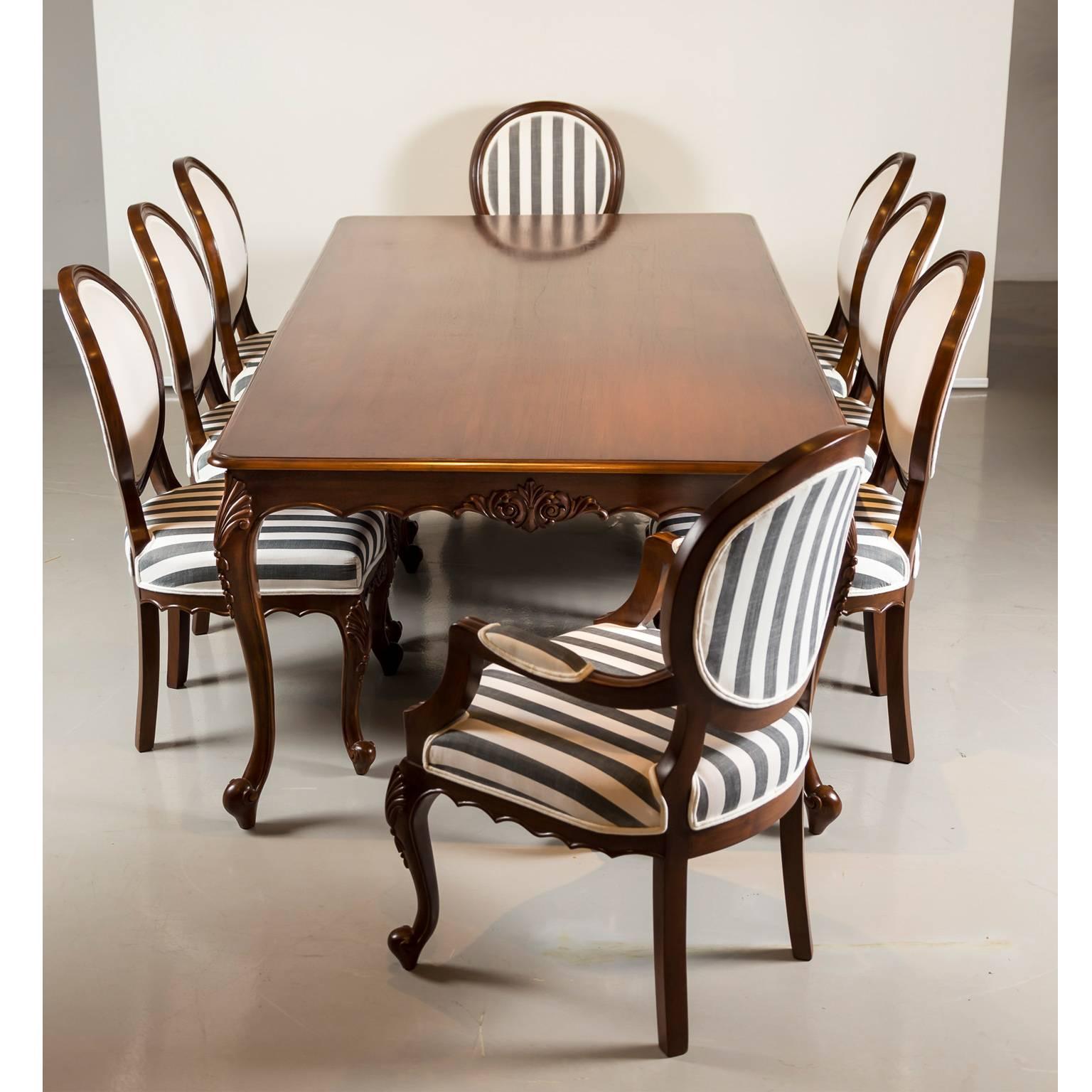 A good size British colonial dining table and a set of eight balloon back chairs made of teak wood. The top of the table, with a moulded edge, is beautifully figured with a carved and serpentine shaped apron. The cabriole legs, with acanthus carving