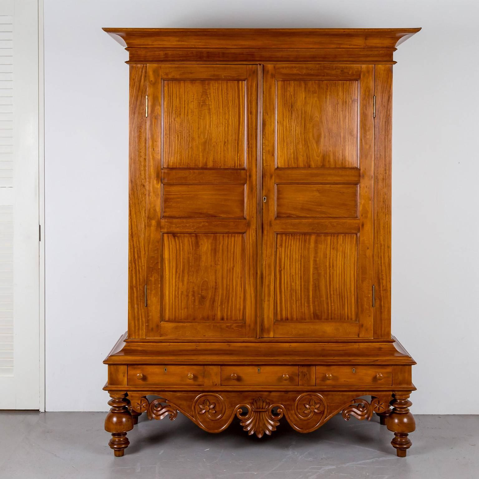 A beautiful Dutch colonial cupboard in satinwood with a deep flaring cornice with moulded edge above a short frieze. 
The double doors, which are constructed with fielded panels, open to an interior with three shelves. 
The lower section of the