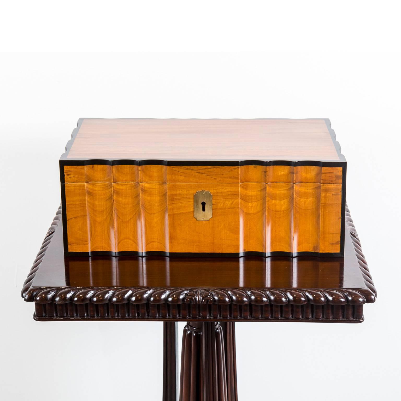 An unusual Dutch colonial satinwood writing box with a brass escutcheon to the front and brass carrying handles on the sides. It has a beautiful serpentine almost wave-like shape on all four sides. It features banding of nicely contrasting ebony on