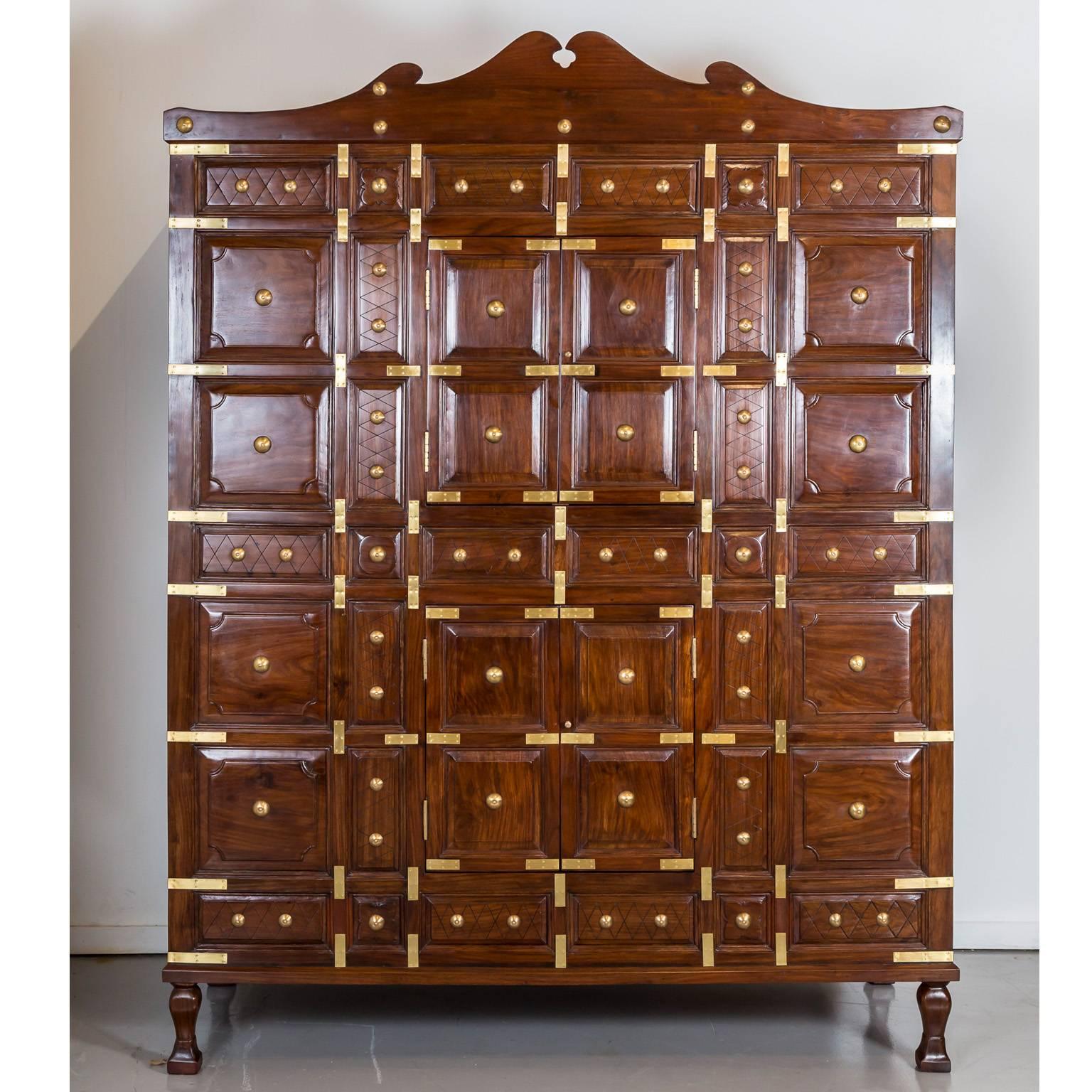 A unique cupboard made of walnut with raised and moulded panels, both decorated and strengthened with brass straps.
It features a serpentine shaped top and four small doors in the middle of the cabinet to give access to the interior. The cupboard