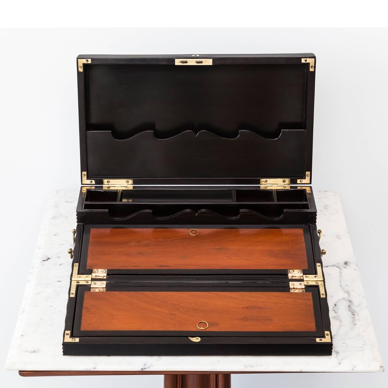 An elegant British Colonial portable desk box, made from beautifully carved ebony. The box has a lid that opens out into a sloping writing surface made of nicely contrasting mahogany wood and consisting of two parts. Underneath each part there is