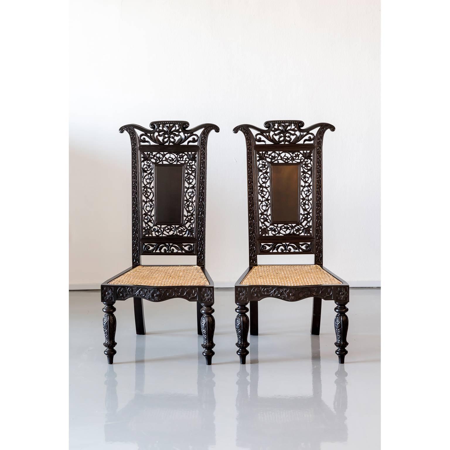 An exceptional pair of British Colonial Prie-Dieu or prayer chairs made in ebony with a caned seat. The back with a solid ebony rectangular block in the middle surrounded by a carved and pierced floral design while the uprights of the back are