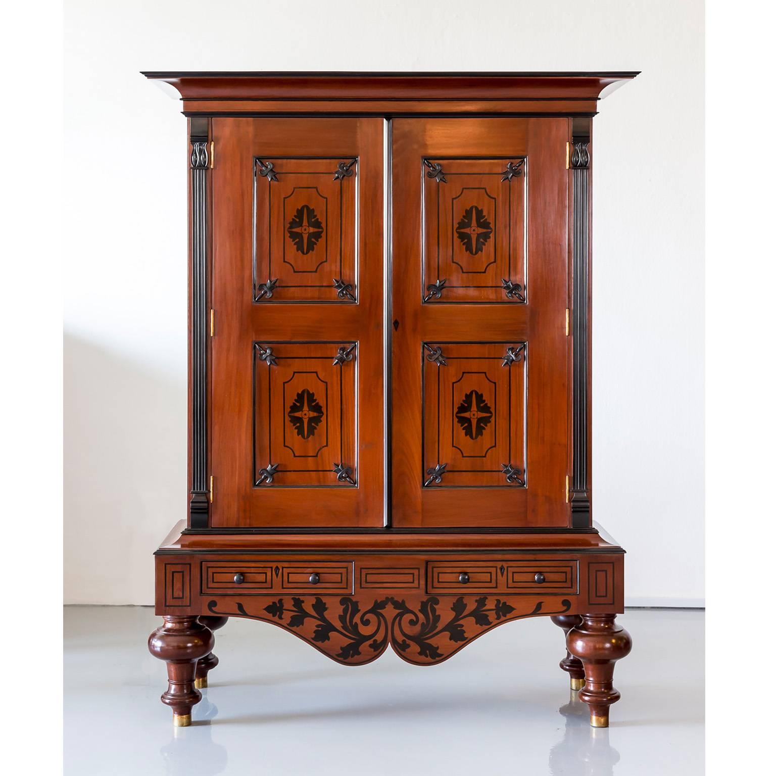 A beautiful Dutch colonial cupboard in mahogany with a deep flaring cornice with an ebony moulded edge above a short ebony frieze. The double doors are constructed with fielded panels inlaid at centre with a design in ebony, surrounded by ebony