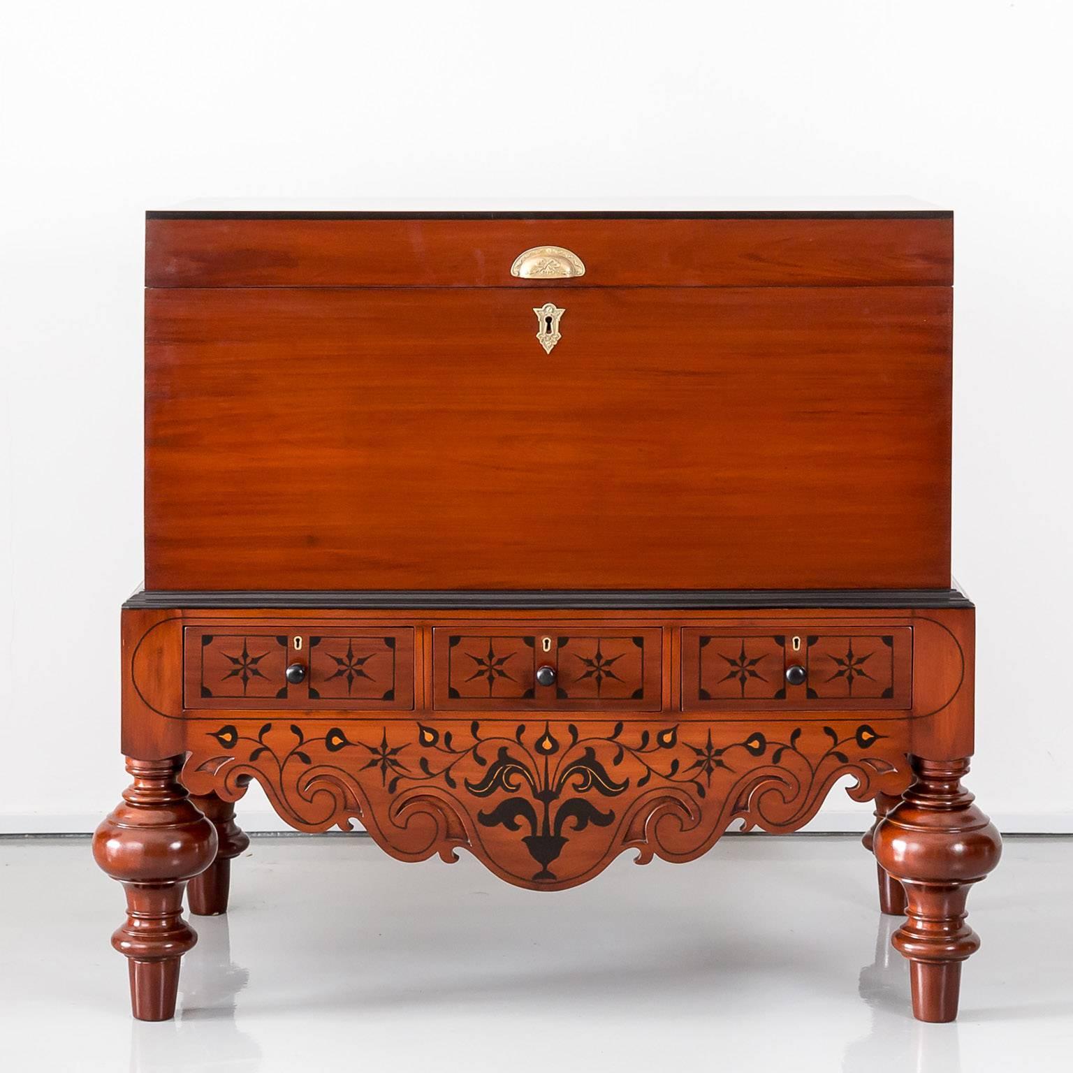 A typical Dutch colonial mahogany chest on stand of solid plank construction with a hinged cover. The hinged cover with a molded ebony edge opens to a plain interior with a small document compartment on the left hand side.
The chest rests on a