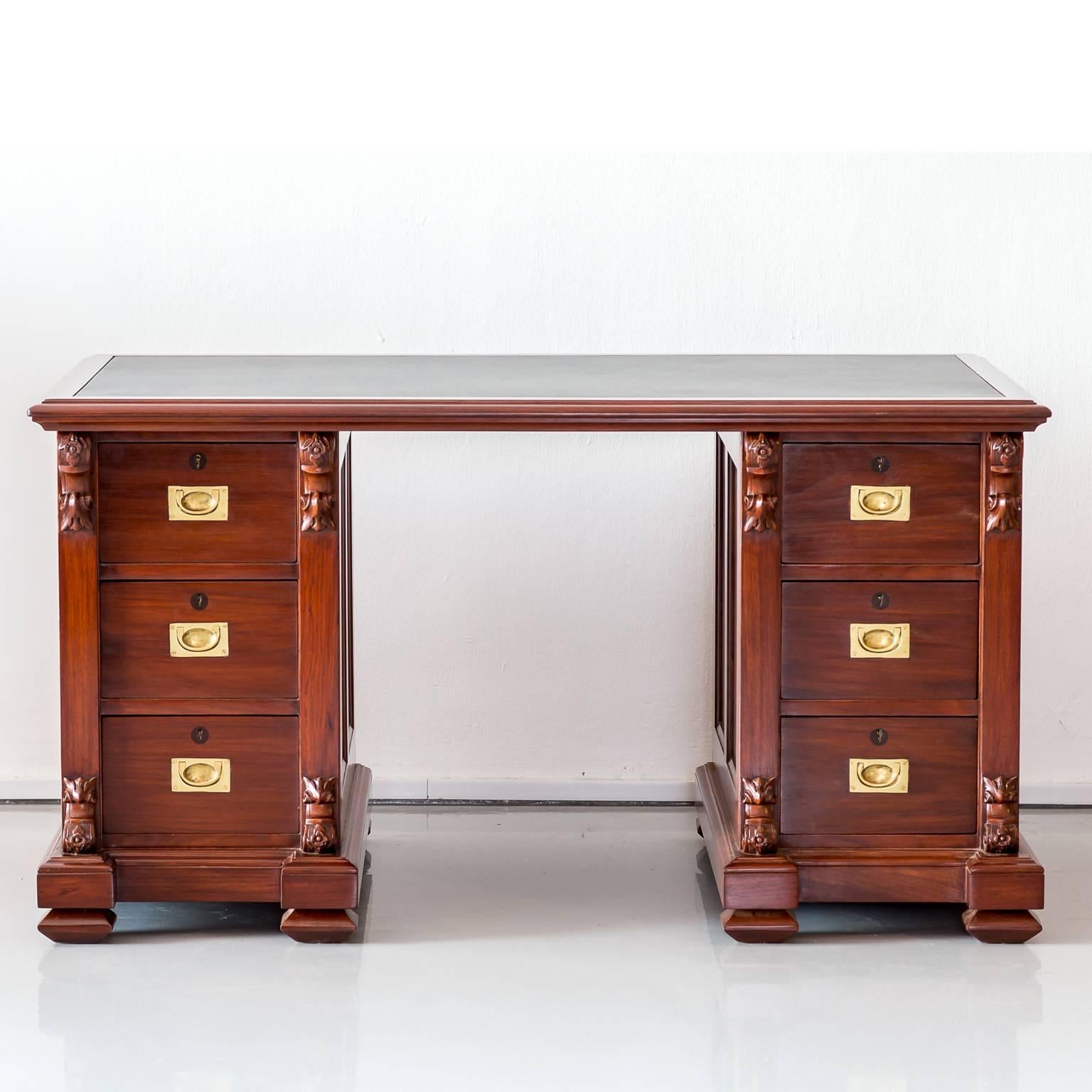 A nice, British Colonial twin pedestal desk in mahogany with a large overhanging top 
above a central kneehole. The top with a new black leather insert. Each pedestal has 
three drawers that are flanked by a decorative carved column. The drawers