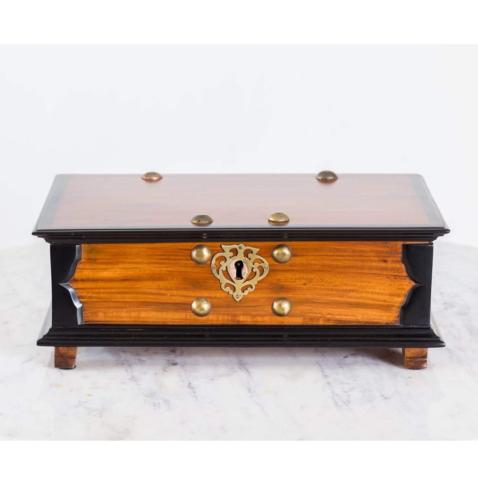 A beautiful Dutch colonial storage box made of nicely contrasting satinwood and ebony. On the sides as well as on the overlapping top and base, the box has a deep moulded ebony edge. The sides have cast bail lift handles against a pierced brass back