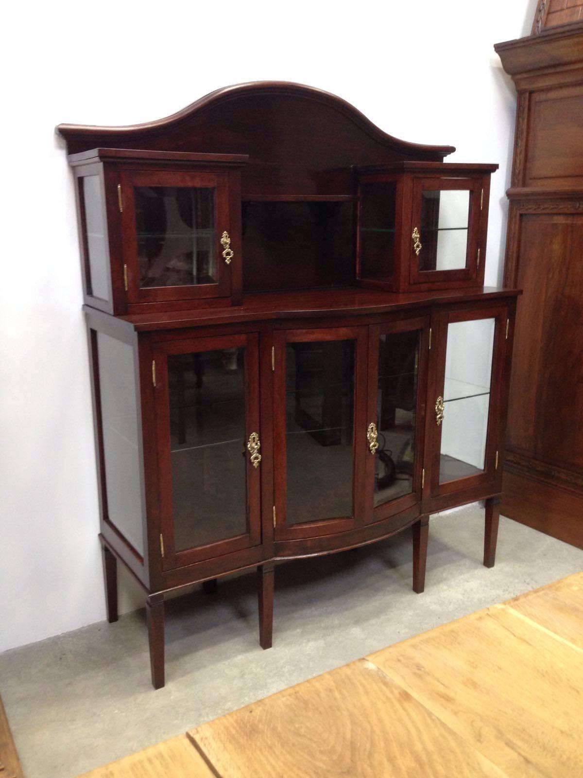 Modernist mahogany buffet with crest.
Grand buffet made of mahogany.
Glass cabinet doors on either side above side cabinets with inside shelves.