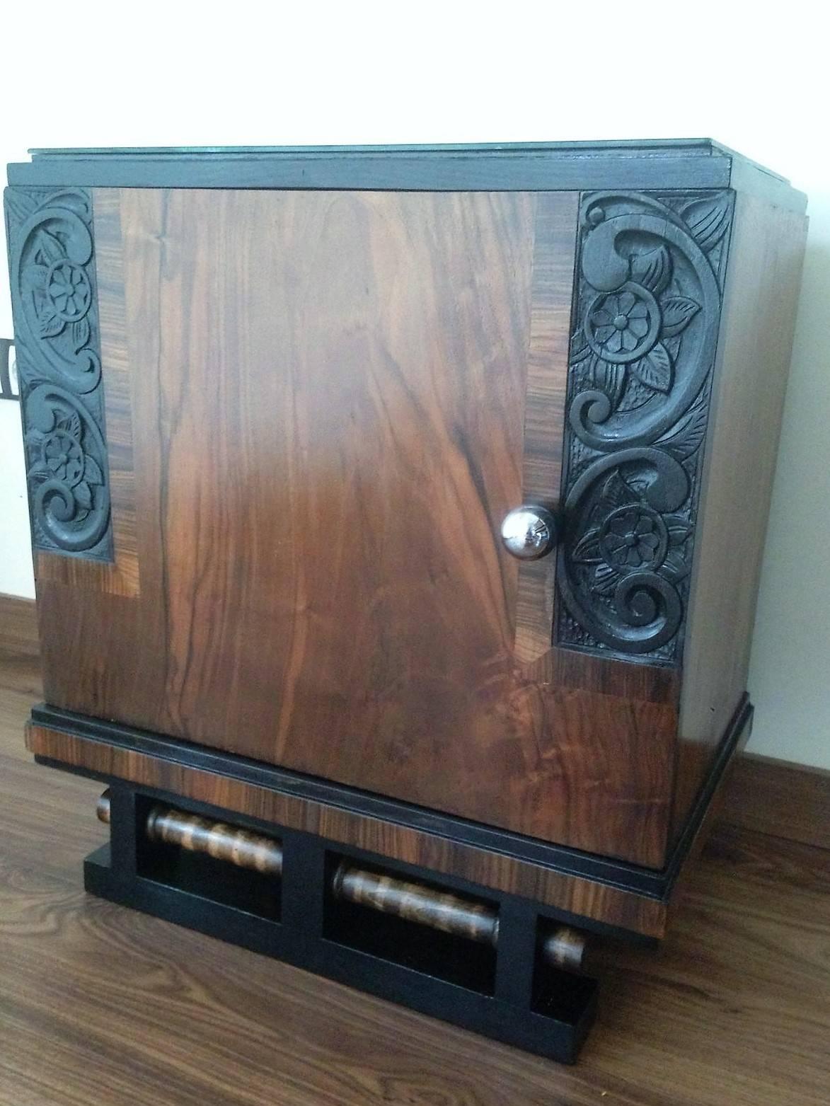 This pair of circa 1930s French Art Deco side cabinets could be used to flank a sofa or as nightstands. Each has a storage compartment with hinged door and narrow open shelves at the sides. One-drawer and one ceramic box. Cabinets are set on