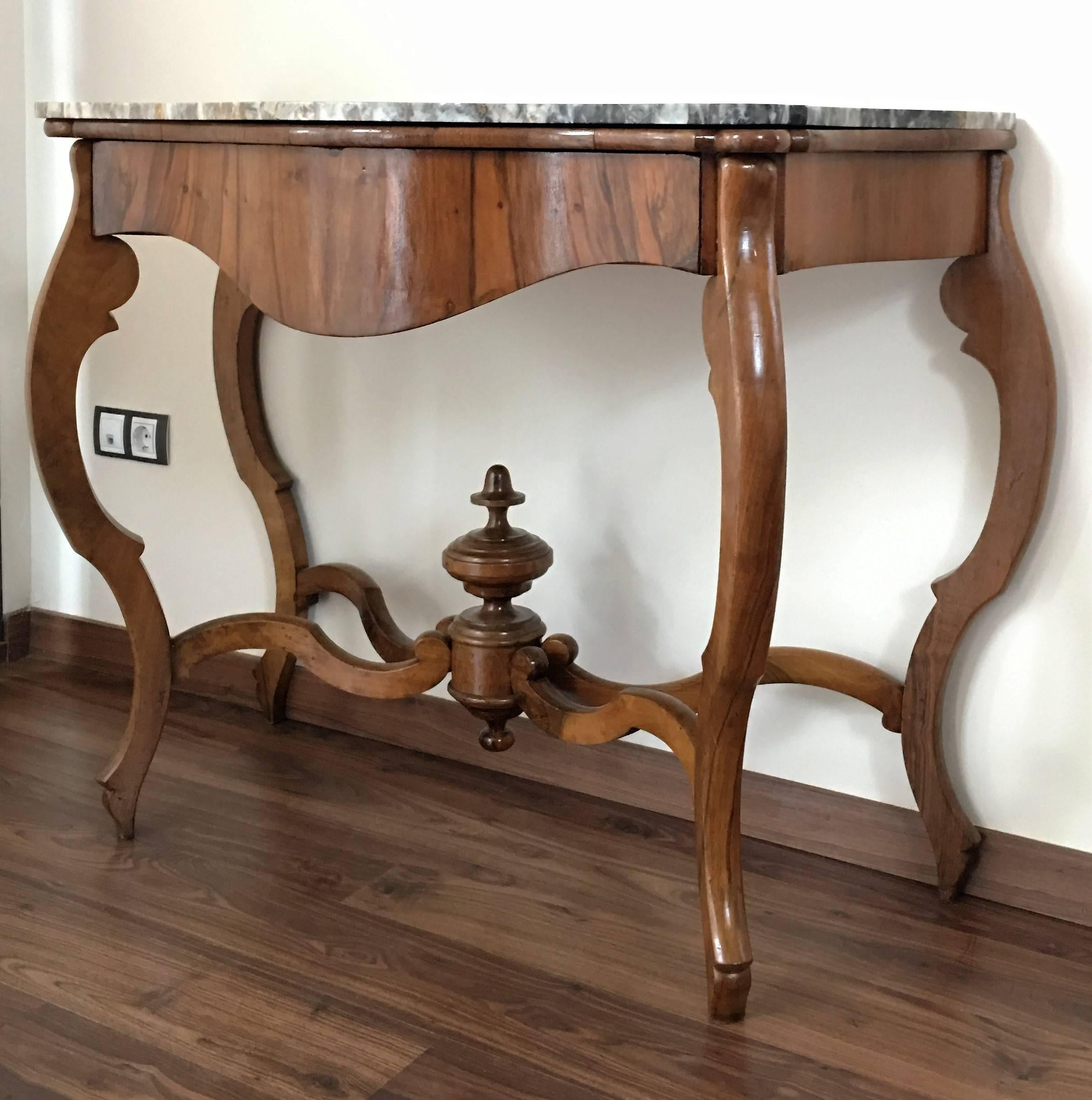 Walnut console table with four curved legs united by an urn stretcher beneath a marble top.