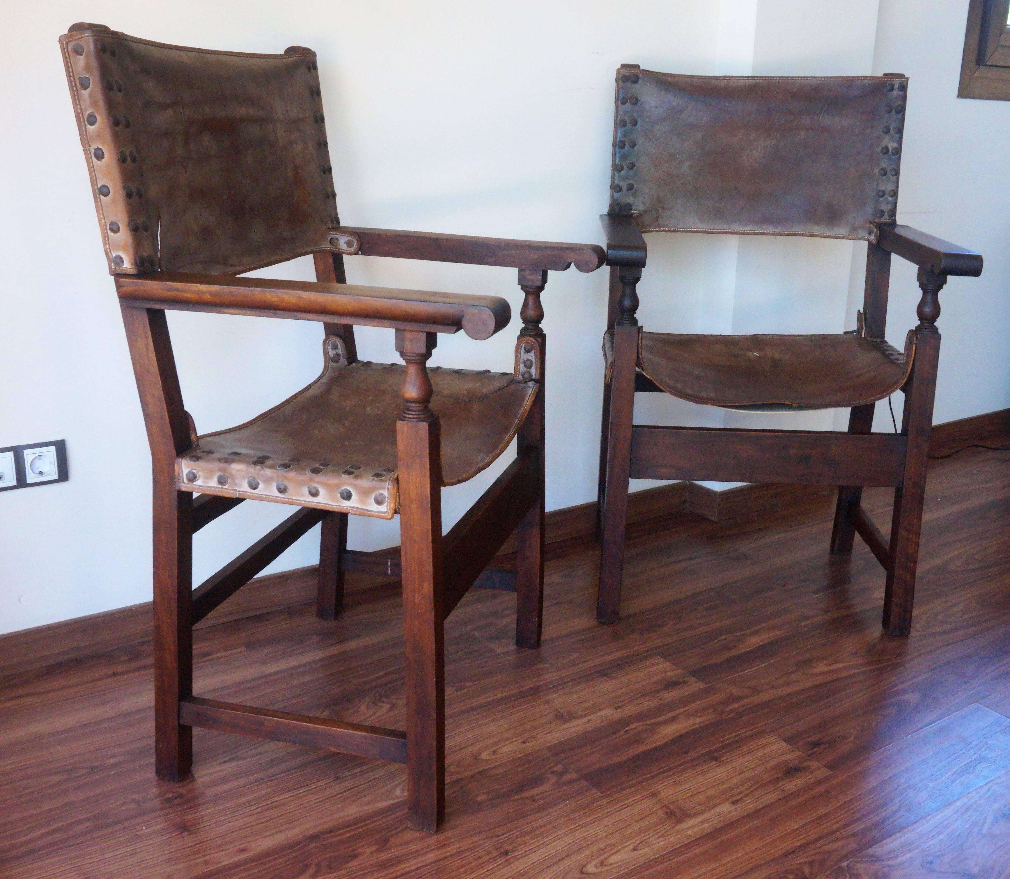Pair of Spanish Colonial style armchairs, having leather seats and backs, brass nailheads and a beautiful patina throughout, 18th century or earlier.

