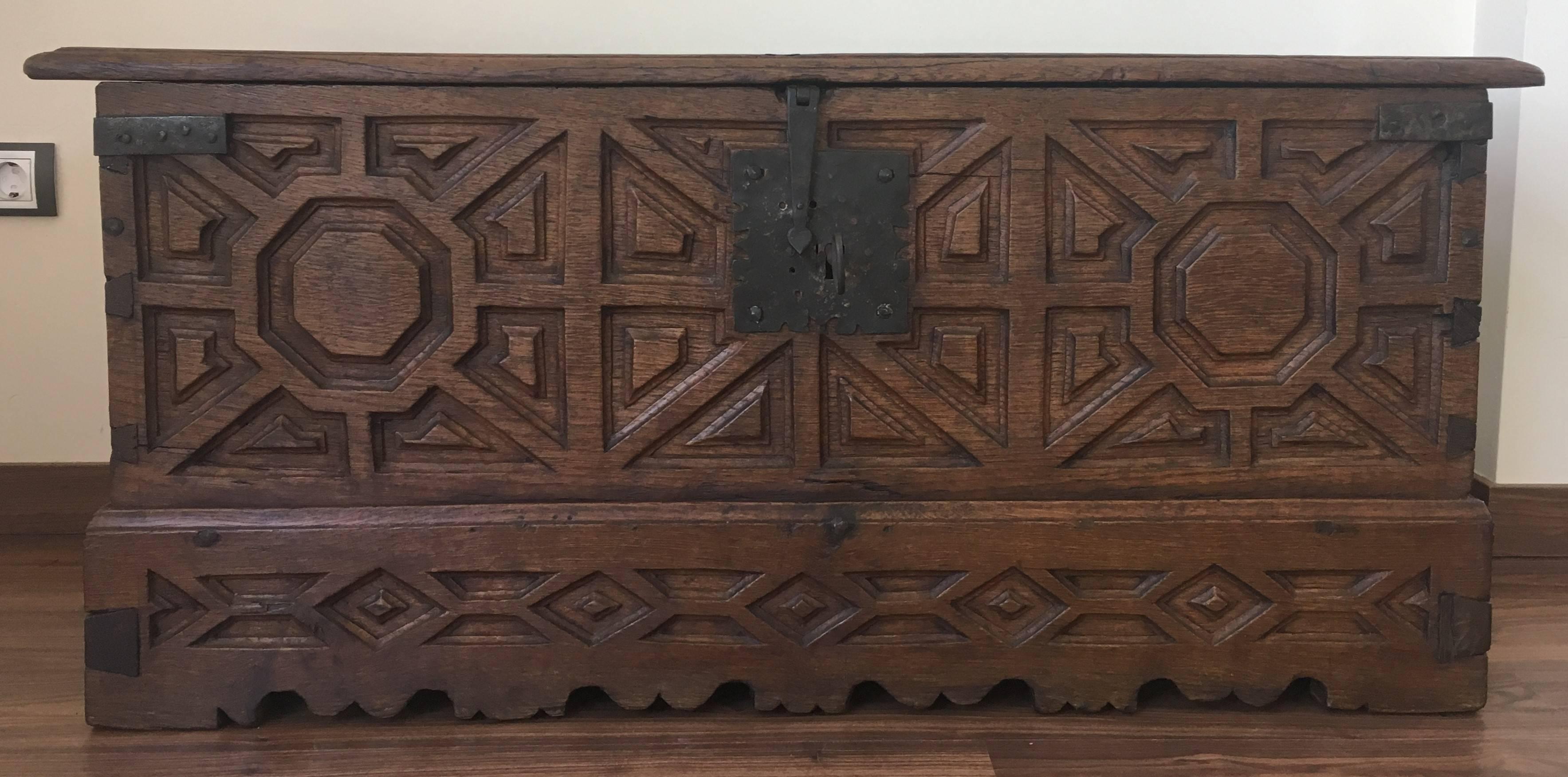 A Spanish 18th century wood coffer. This Spanish trunk from the 18th century features beautifully visible dovetail joints down each corner side and a scalloped skirt which is adorned with geometrical carvings. The trunk's interior offers a large