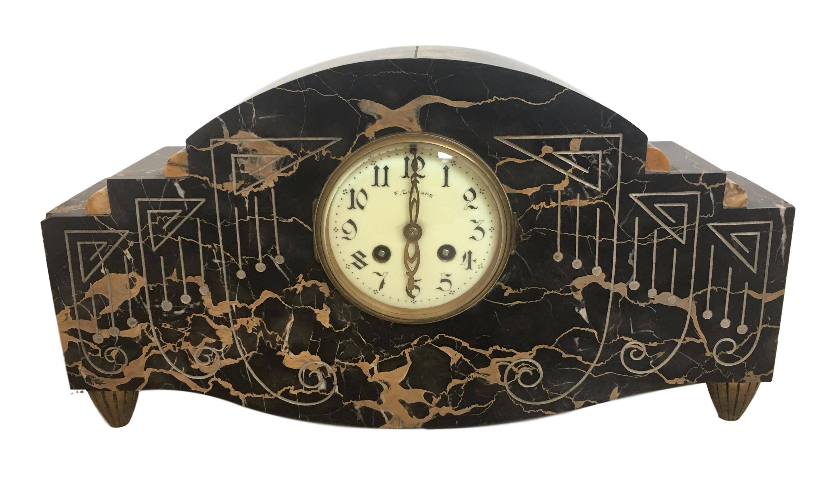 Art Deco clock with ornamentals carved motifs and bronze legs.

Measurements:
Clock H 9.25in, D 4in, W 16.9in
Garniture (each piece) H 7.28in, D 3.3in, W 5.3in.