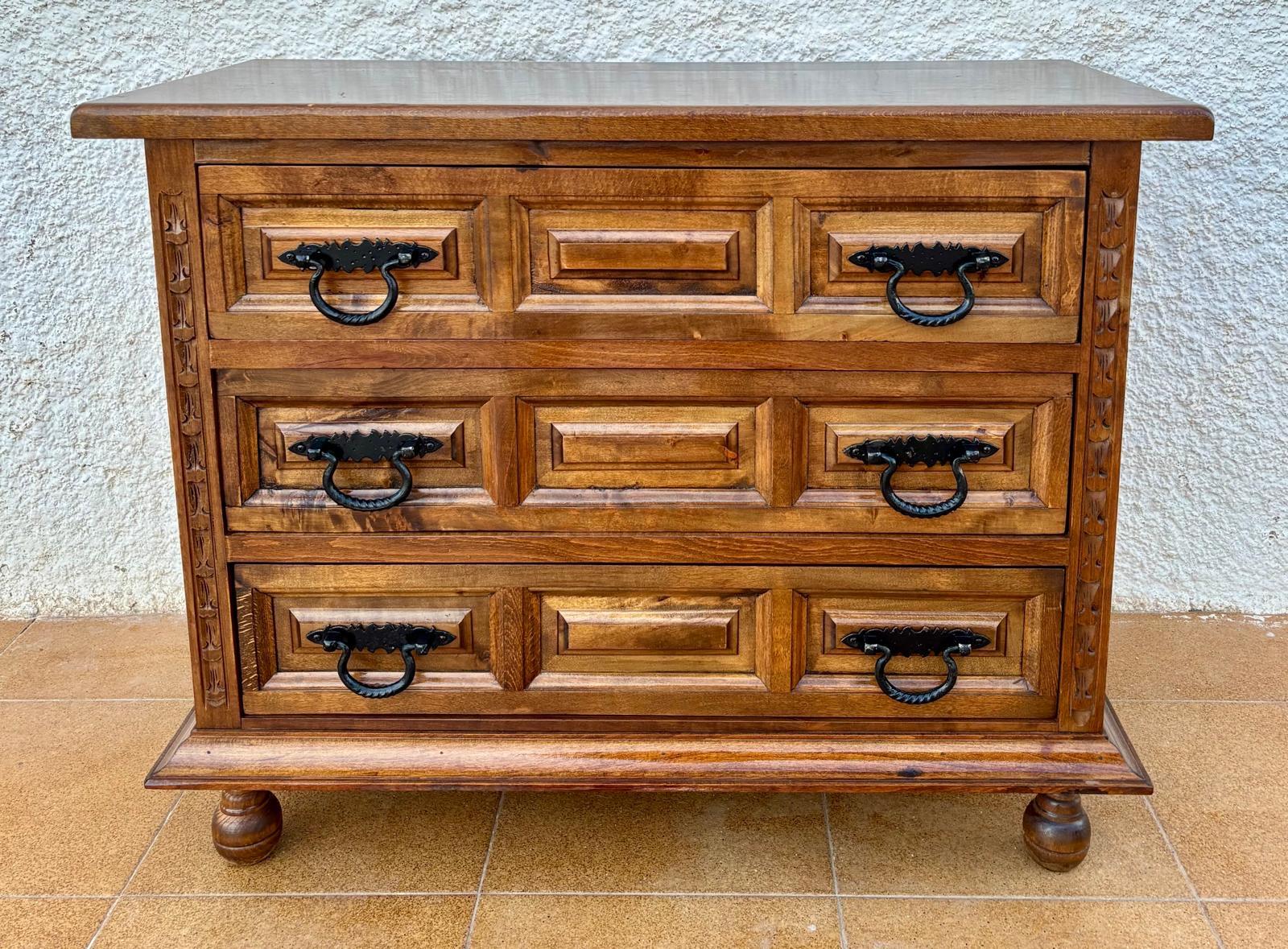 Castilian chest of drawers from the early 20th century, it has three large walnut wood drawers decorated with panels on its front and with iron handles.
Its sides are also decorated with panels and it stands on four round legs.