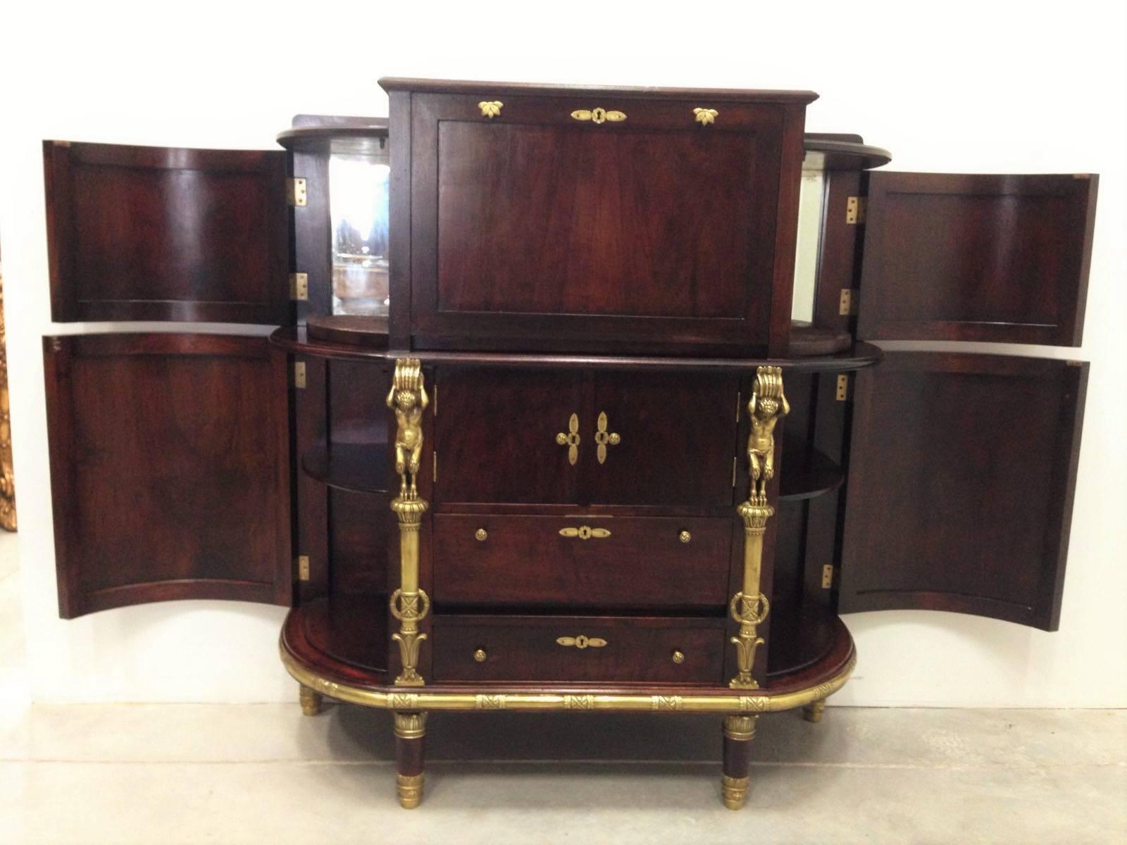 This bar is made of sturdy mahogany. The forefront’s unique flamed finish is simplistic yet stunning, and the bar is adorned with brass drawer pulls, feet, and other decoration to add regal flair. As far as storage goes, there are three drawers on