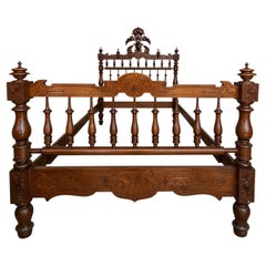 Ornately Carved Antique Wooden Bed Frame with Turned Spindles and Crest