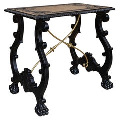 Mesa de centro antigua de madera tallada ebonizada con travesaños de latón y patas en forma de garra