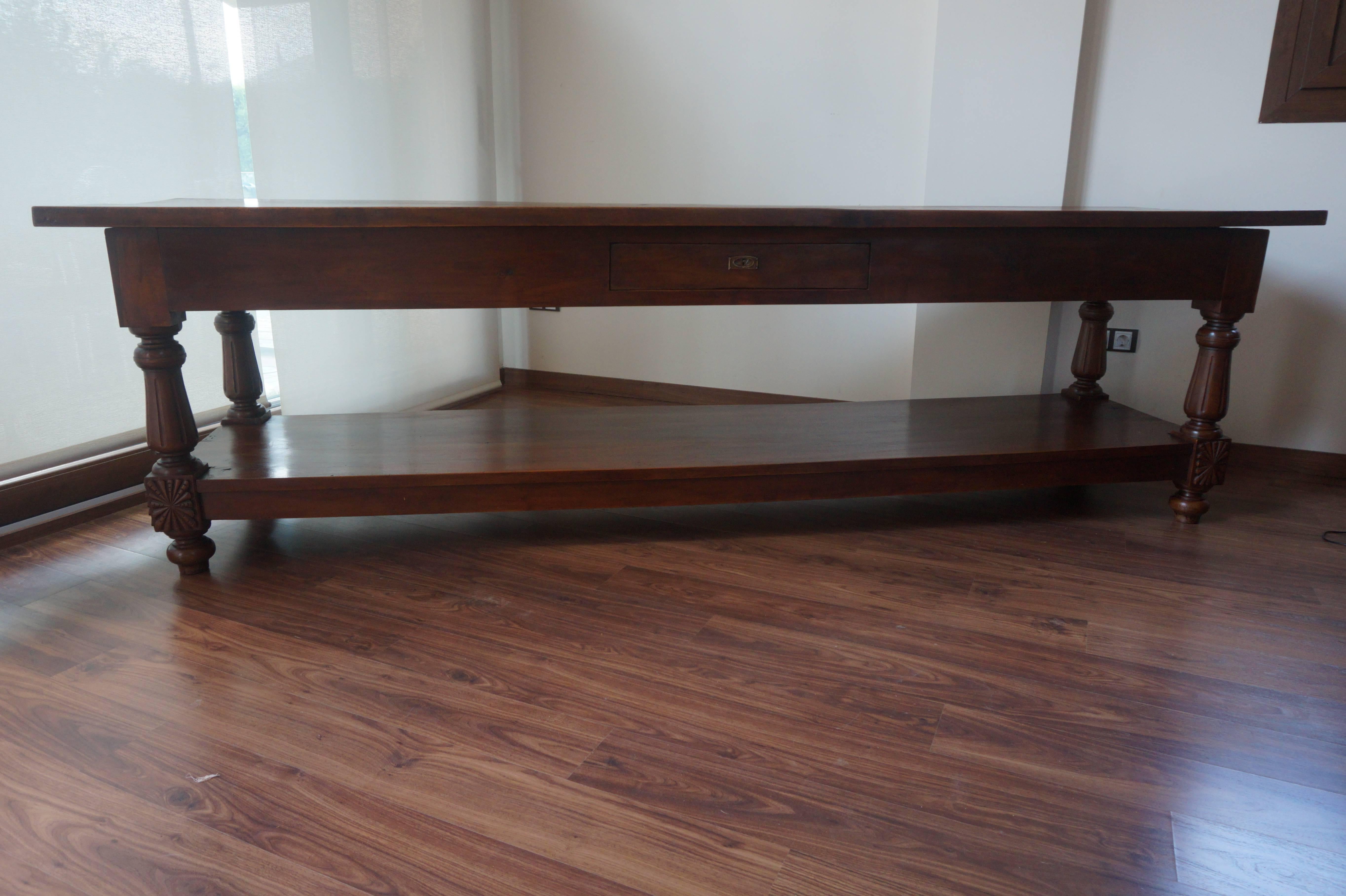 19th century refectory walnut farm table. This solid and utilitarian table is raised on four topie shaped feet with full bottom tier with a beautiful ornamental carved.
Central drawer with original lock.


