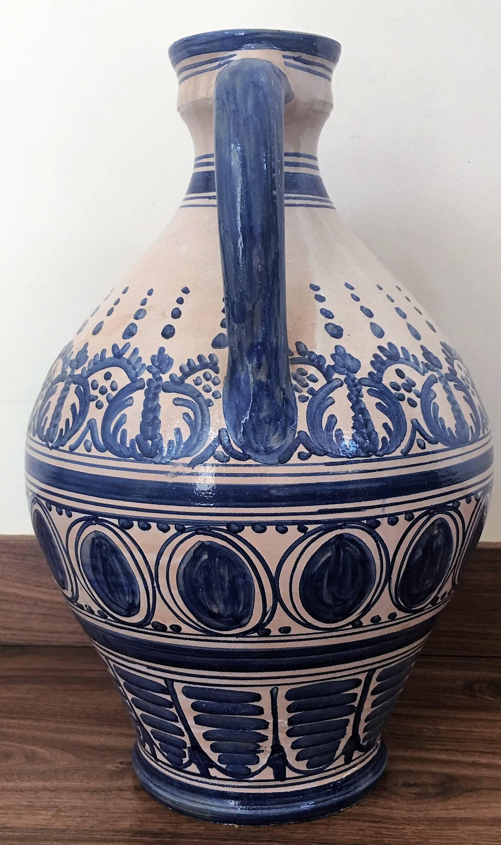 A striking Spanish glazed earthenware two-handled blue and white painted urn with foliate molded handles, the body underglaze blue decorated.