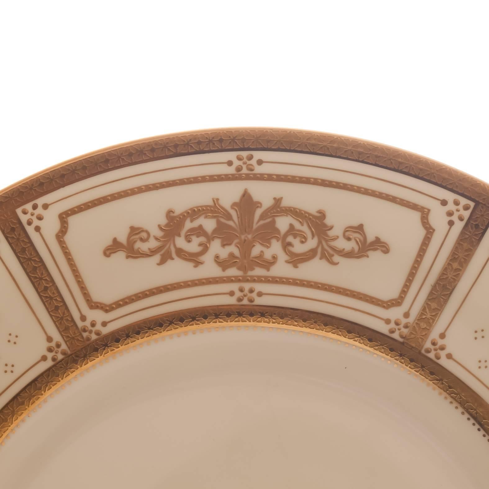 A finely detailed set by one of England's great porcelain manufacturers: Minton. An unique design of 24-karat acid etched gilt bands and panels with detailed and exquisite raised tooled gold in an Art Deco design. Custom ordered through the fine
