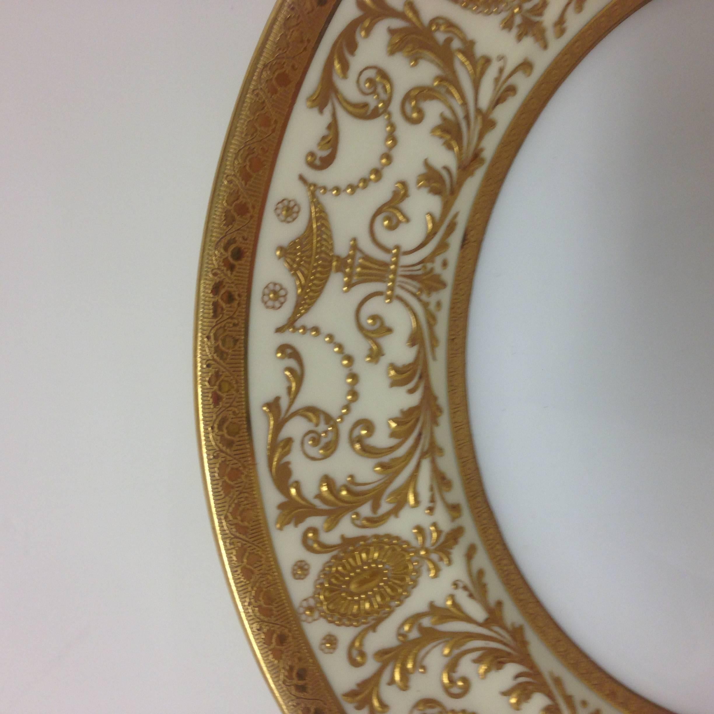Absolutely stunning set of detailed and hand raised tooled gilding set of dinner or presentation plates. Acid etched gold banding and nice clear centers with a Classic hint of cream on the shoulders of the plates. Custom retailer hall mark with