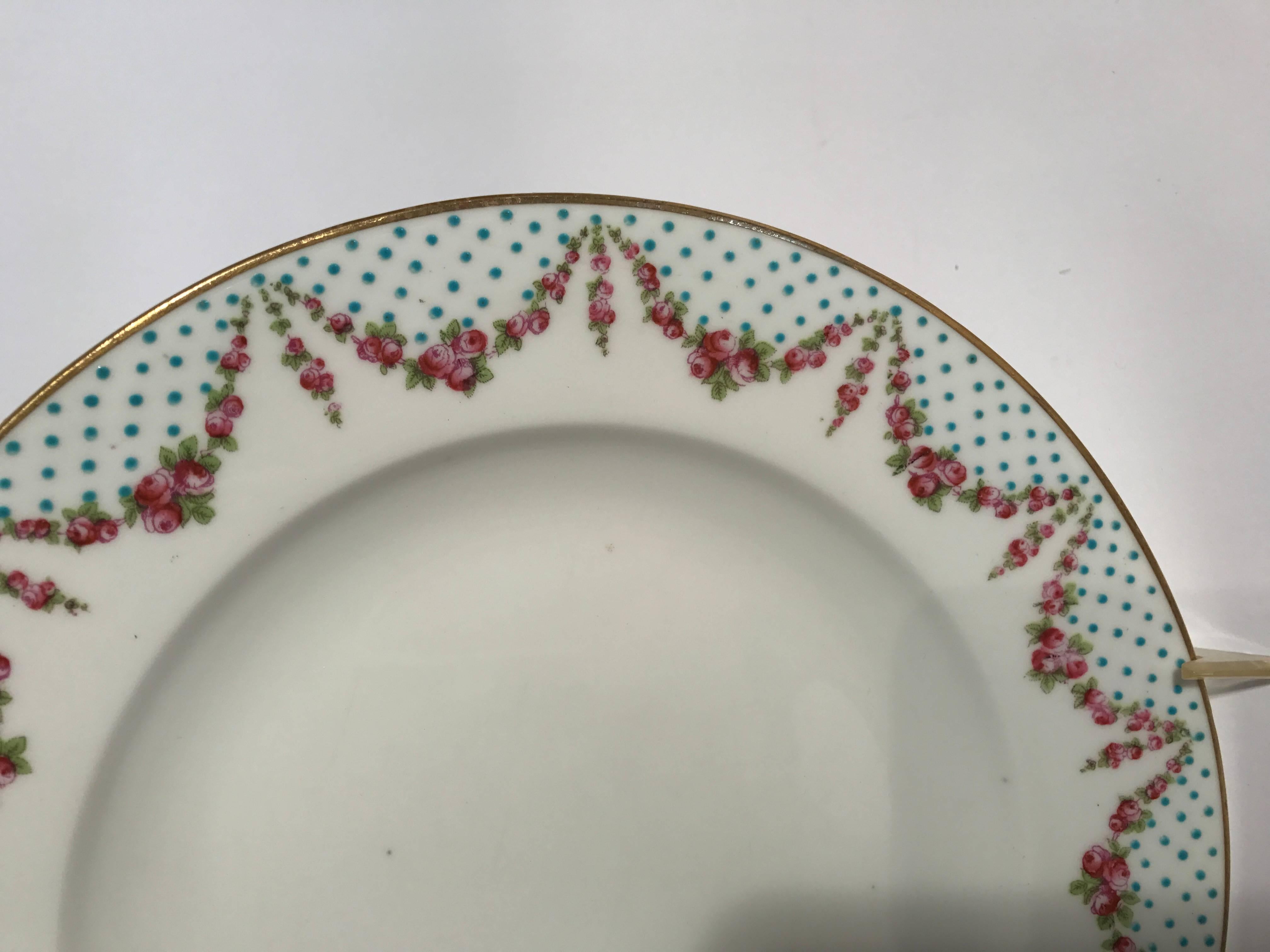 A charming set of antique English fine bone porcelain dinner plates. These feature lovely hand-painted roses and hand enameled 