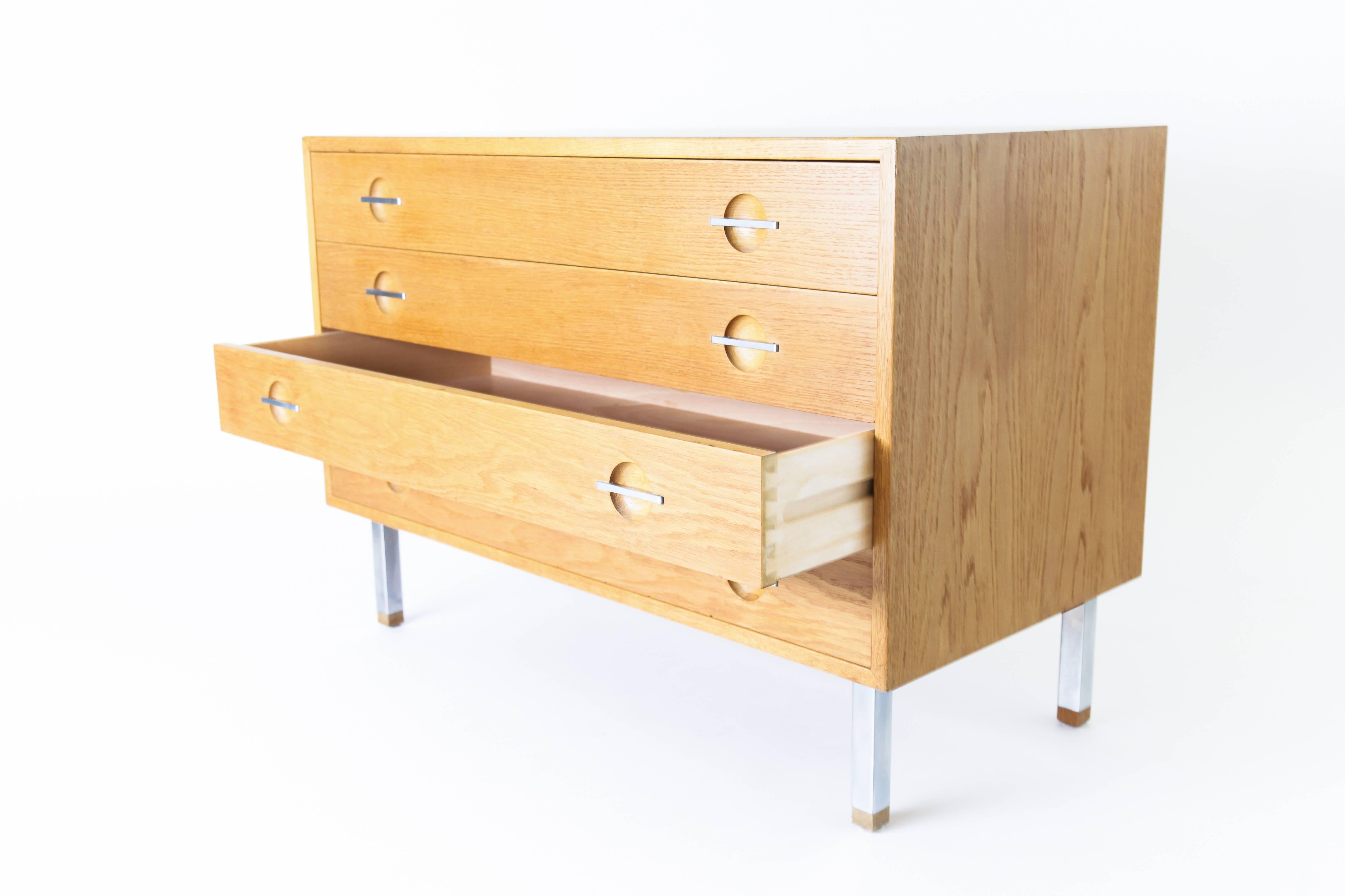 Chest of four drawers, oak and teak, steel feet and handles. 
Danish work by Hans Wegner, edited by Ry Mobler, circa 1960.