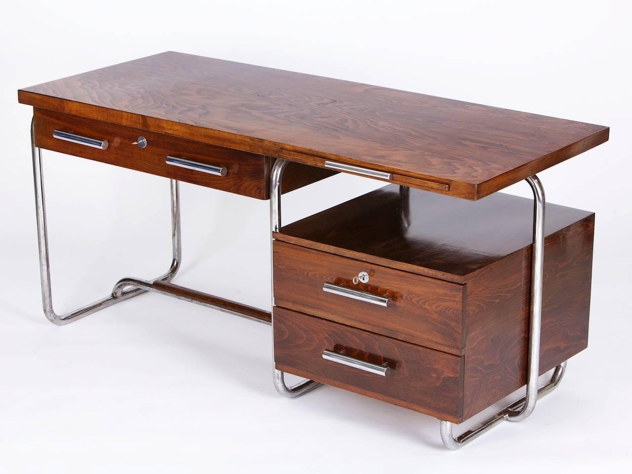 This chromed tubular steel desk was designed and produced by Hynek Gottwald in the early 1930s in former Czechoslovakia. 
The wooden parts has been restored and the tubular steel construction remained in a good original vintage condition with some