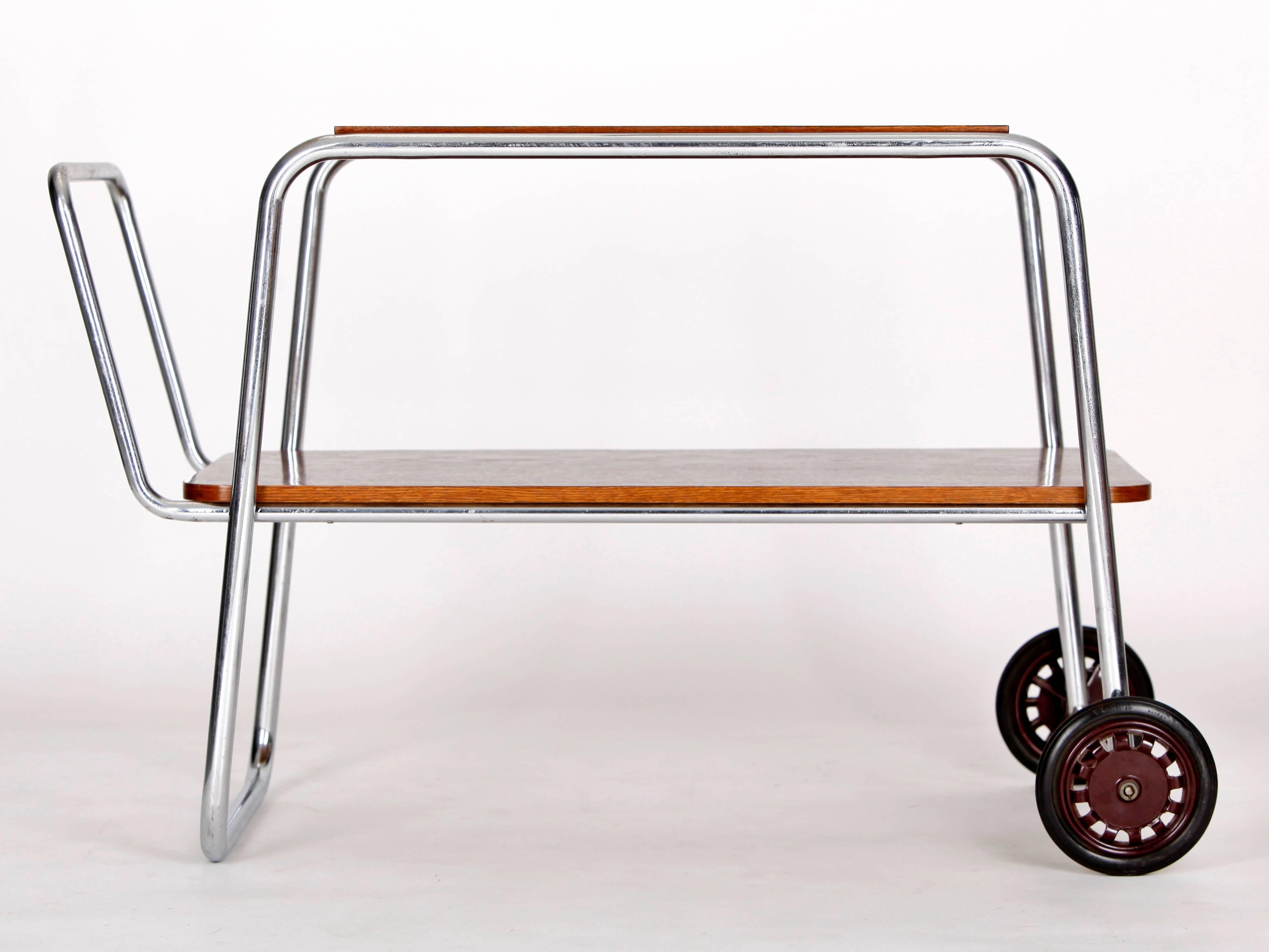 This bar or serving cart was designed and made by the Czech company Slezak and features original chrome plating with a little patina. The wooden panels have been restored.
