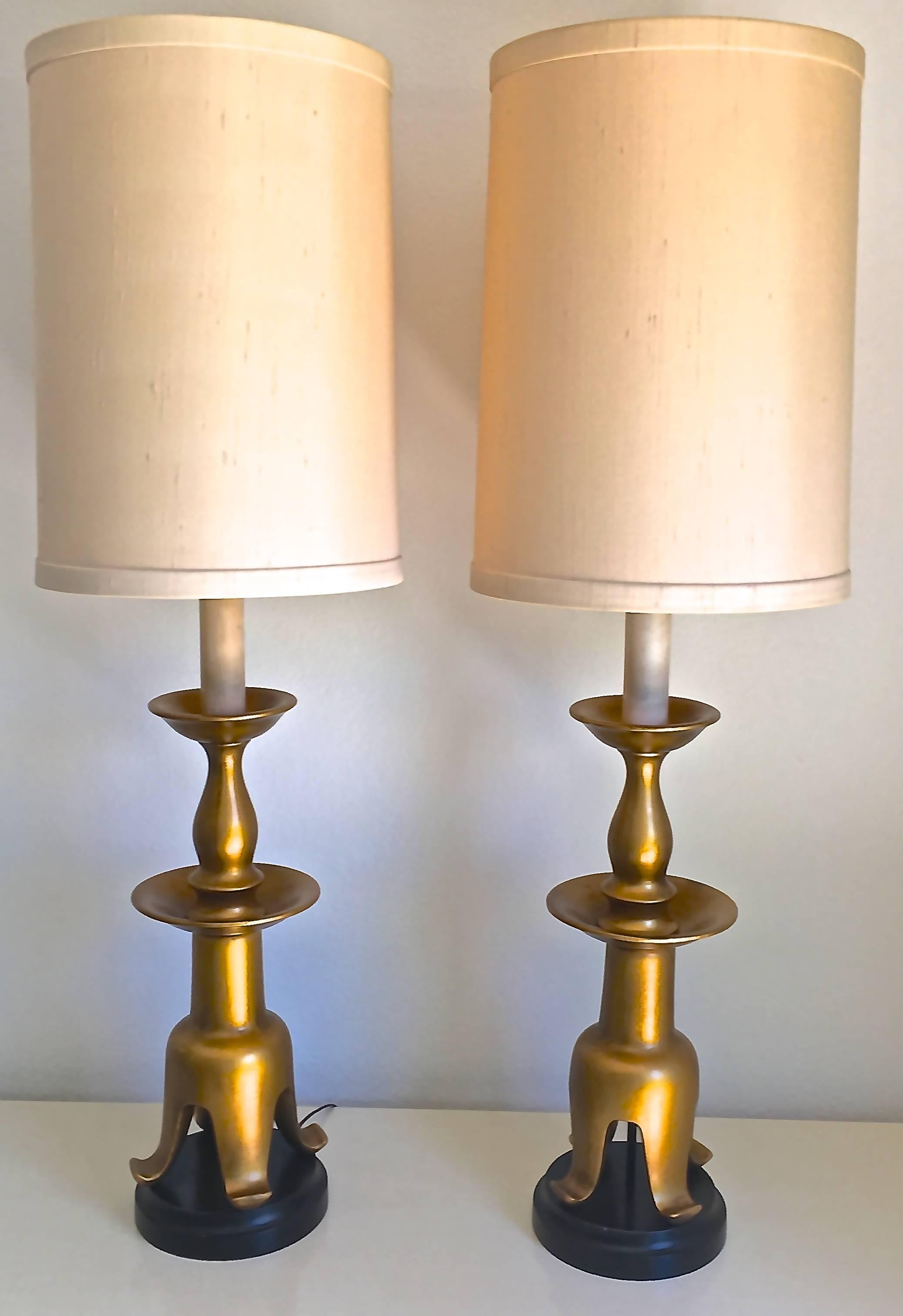 Attributed to James Mont, this pair of handsome tiered giltwood lamps with cat's paw bases on ebony risers are the perfect transitional lamps. Modern simplicity, chinoiserie details, Hollywood Regency glamour, these would be striking in any