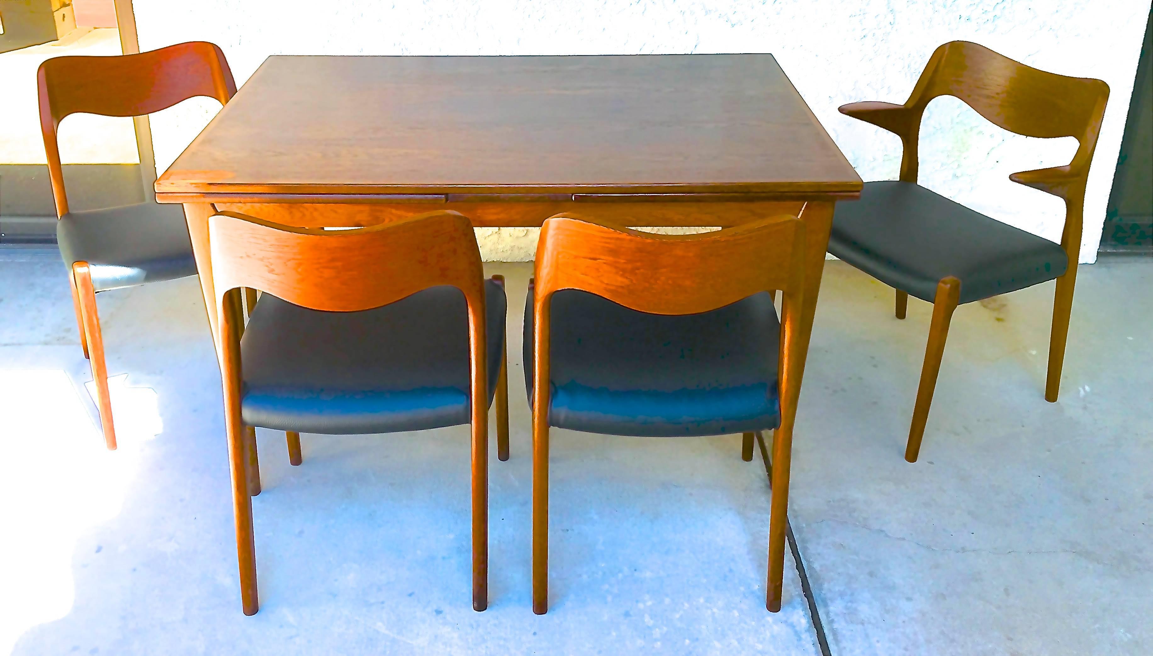 Exquisite rosewood dining table, circa 1950s designed by Niels Otto Møller for Danish Furniture Company. Table is model no. 12 and seats four-six, extending each end to seat up to ten. Set includes four rosewood chairs in black leatherette - three
