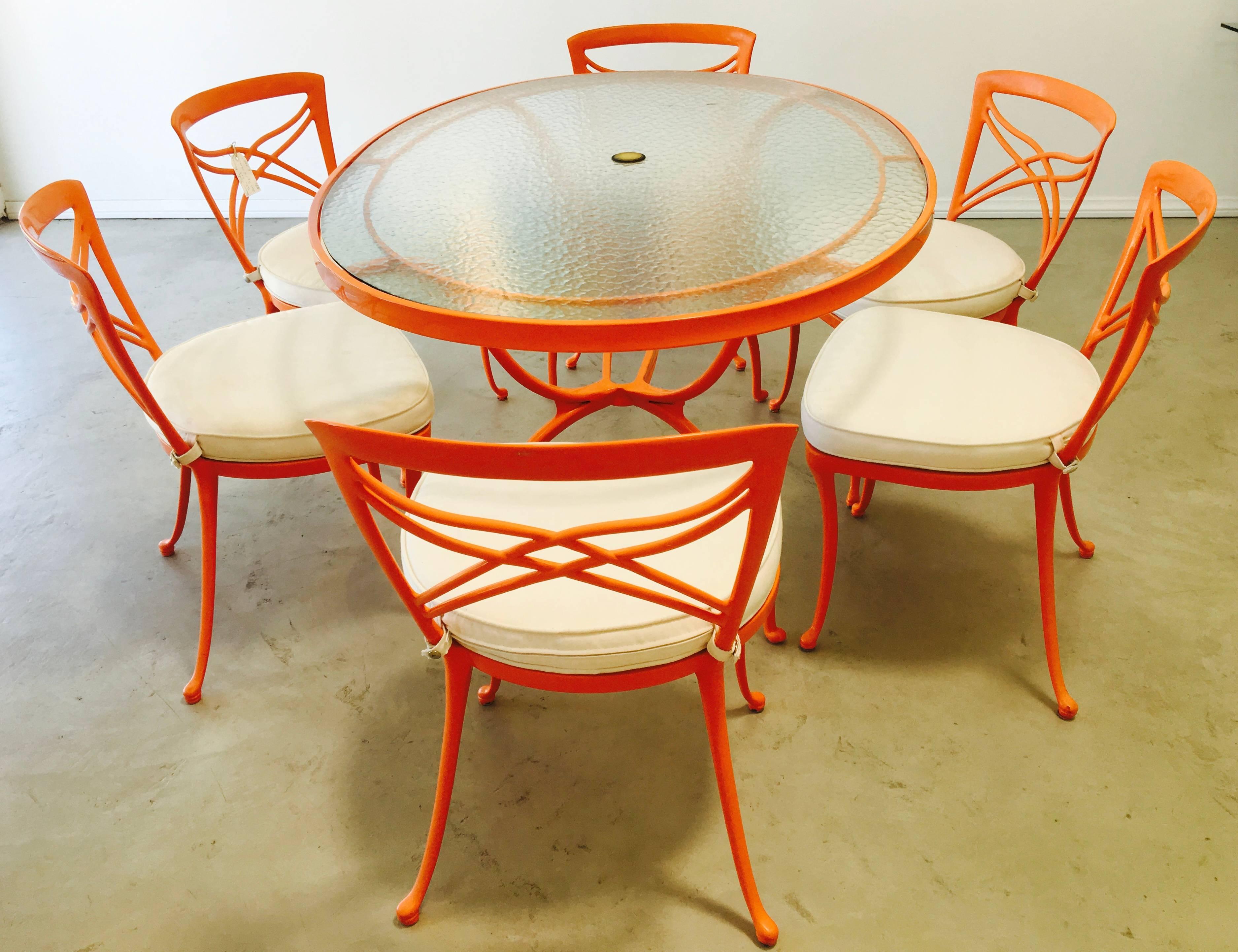 1960s oval patio dining set with six chairs by Brown Jordan is a striking example of Mid-Century Modern Hollywood Regency design. Orange enamel frames pair nicely with off-white washable canvas seat cushions, and the bubble glass top has an opening