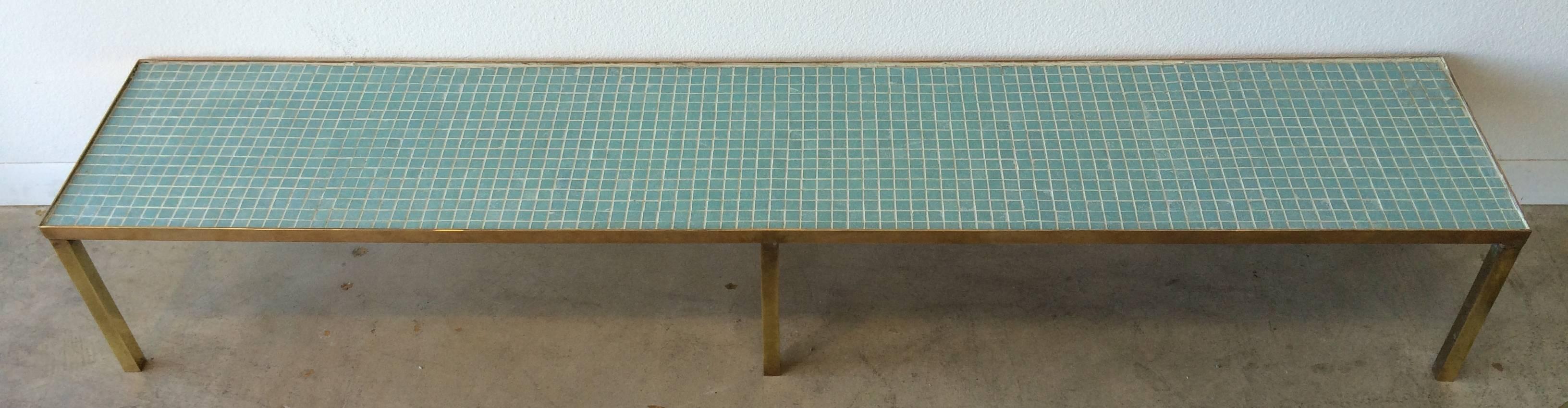 Clean-lined, long, solid brass base supports a wood top tiled in aqua glass mosaic tiles. This piece may be used effectively as a cocktail table or low bench. Perfect proportions in front of a bank of sliding glass or floor-to-ceiling windows.